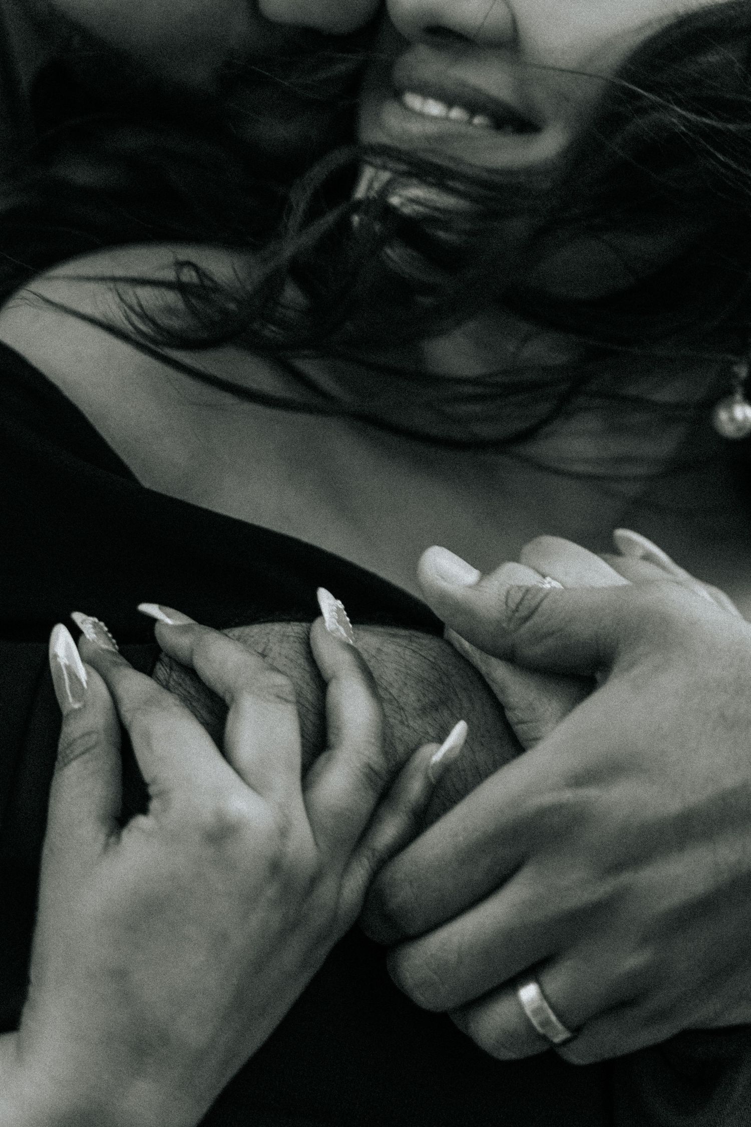 Black and white photograph showing gentle hands and wedding rings in an intimate moment.