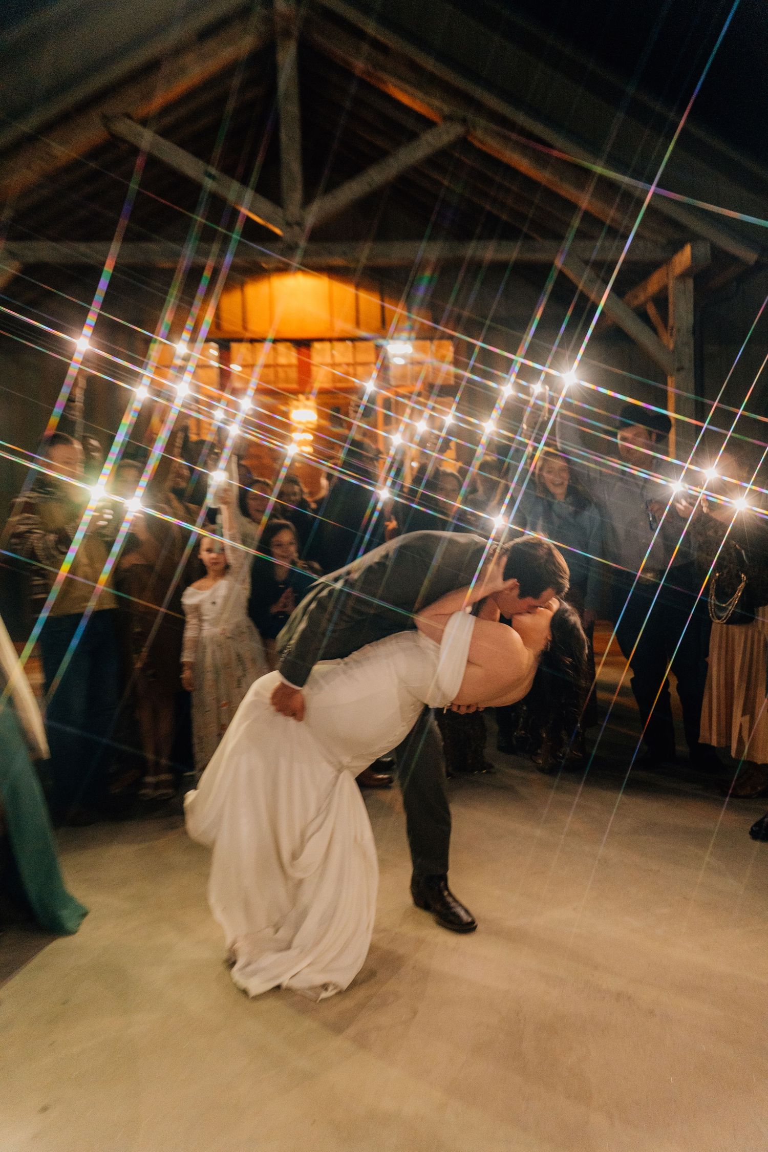 Wedding dance scene in a rustic barn venue with twinkling lights overhead.