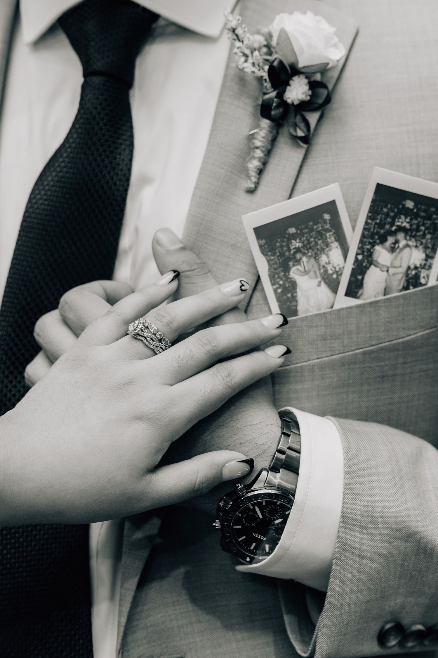 Black and white close-up of hands adjusting formal attire and watch details.