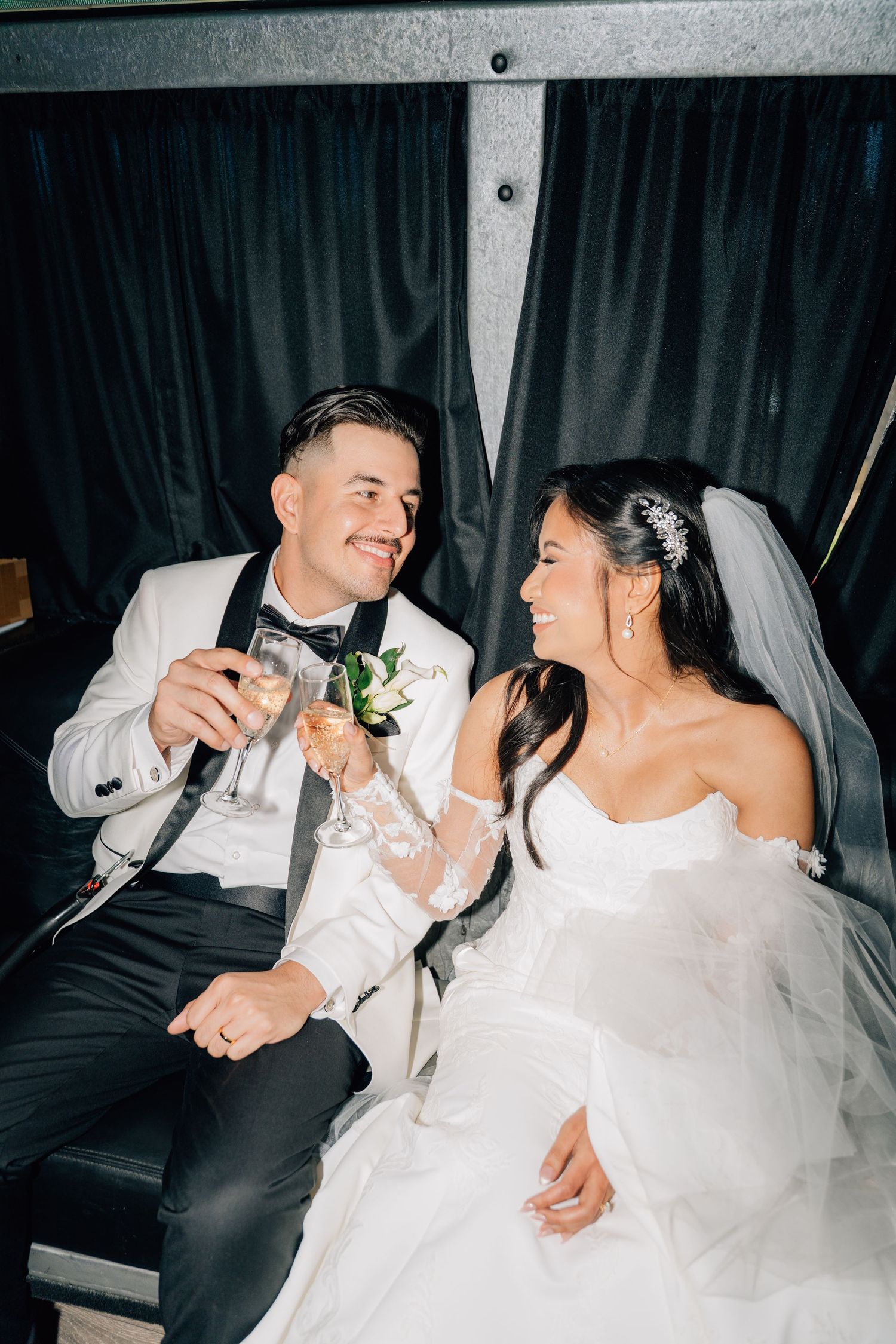 Couple shares intimate moments together in formal wedding attire inside a dimly lit space.