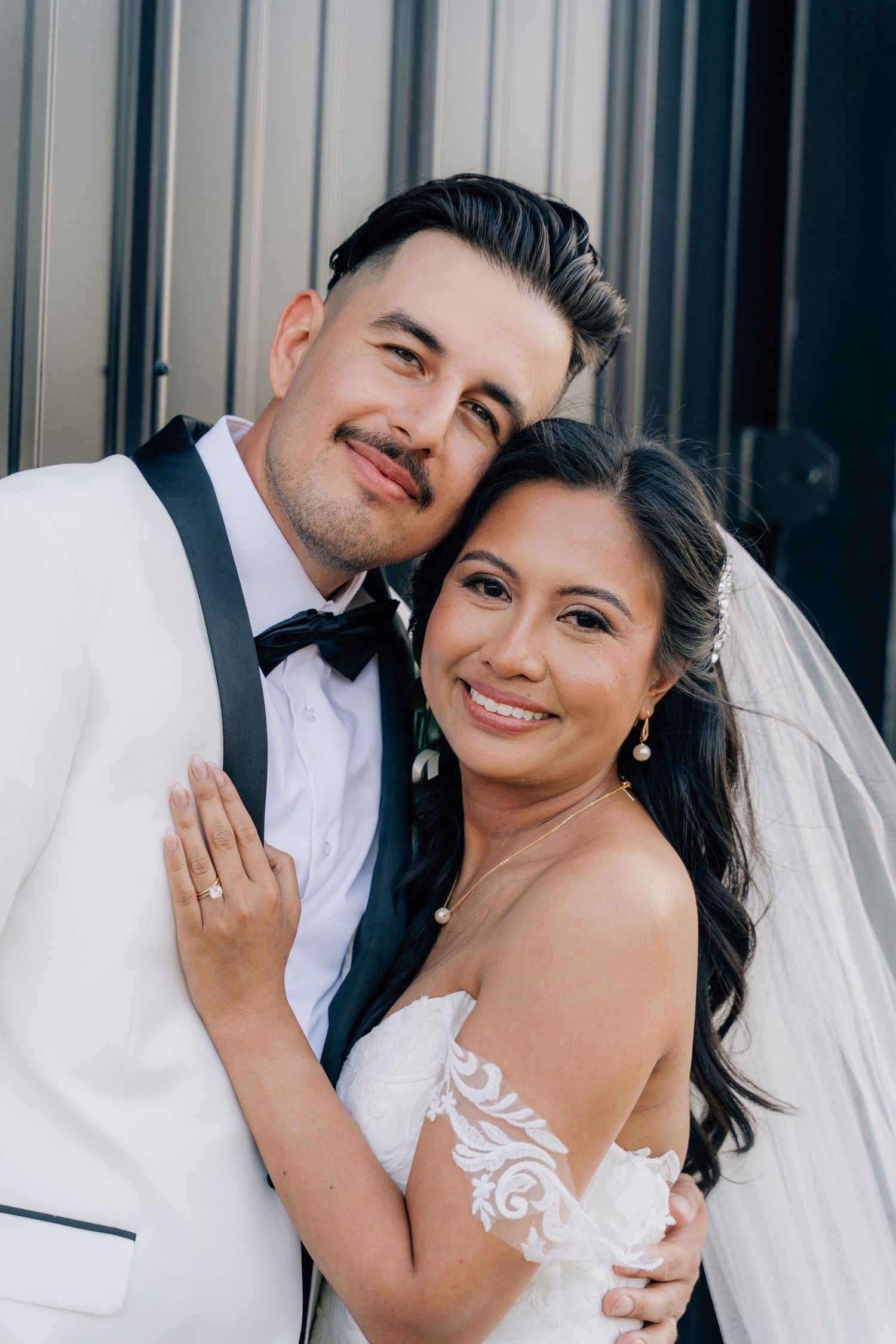 Elegant wedding couple sharing a joyful moment against an industrial backdrop.