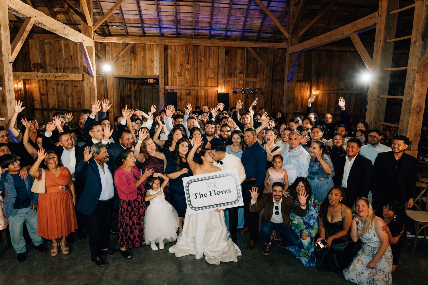 Panoramic view of wedding guests gathered in a rustic barn venue.