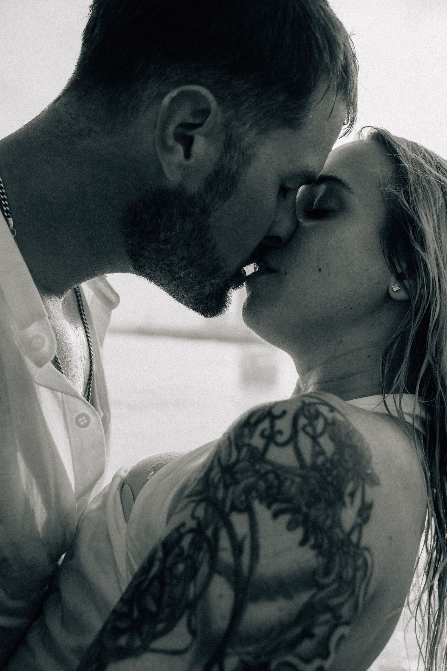 Black and white intimate portraits showing visible tattoo art and tender moments.