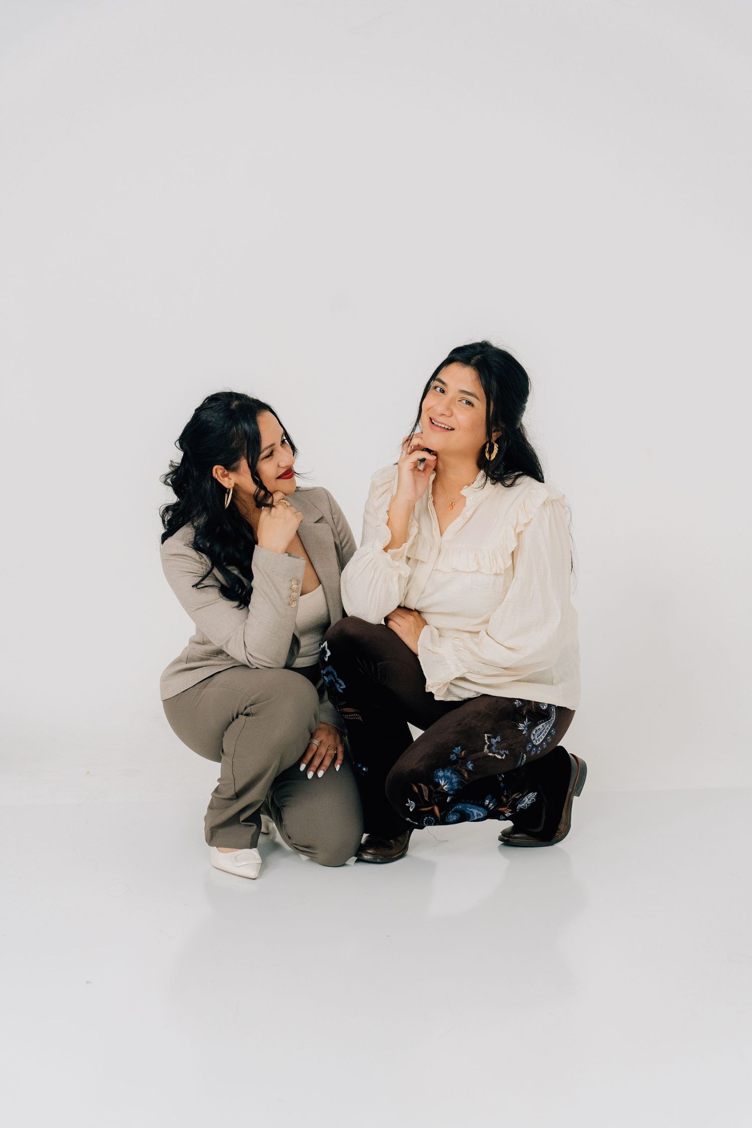 Two people in casual attire share intimate conversations while sitting on a white floor.