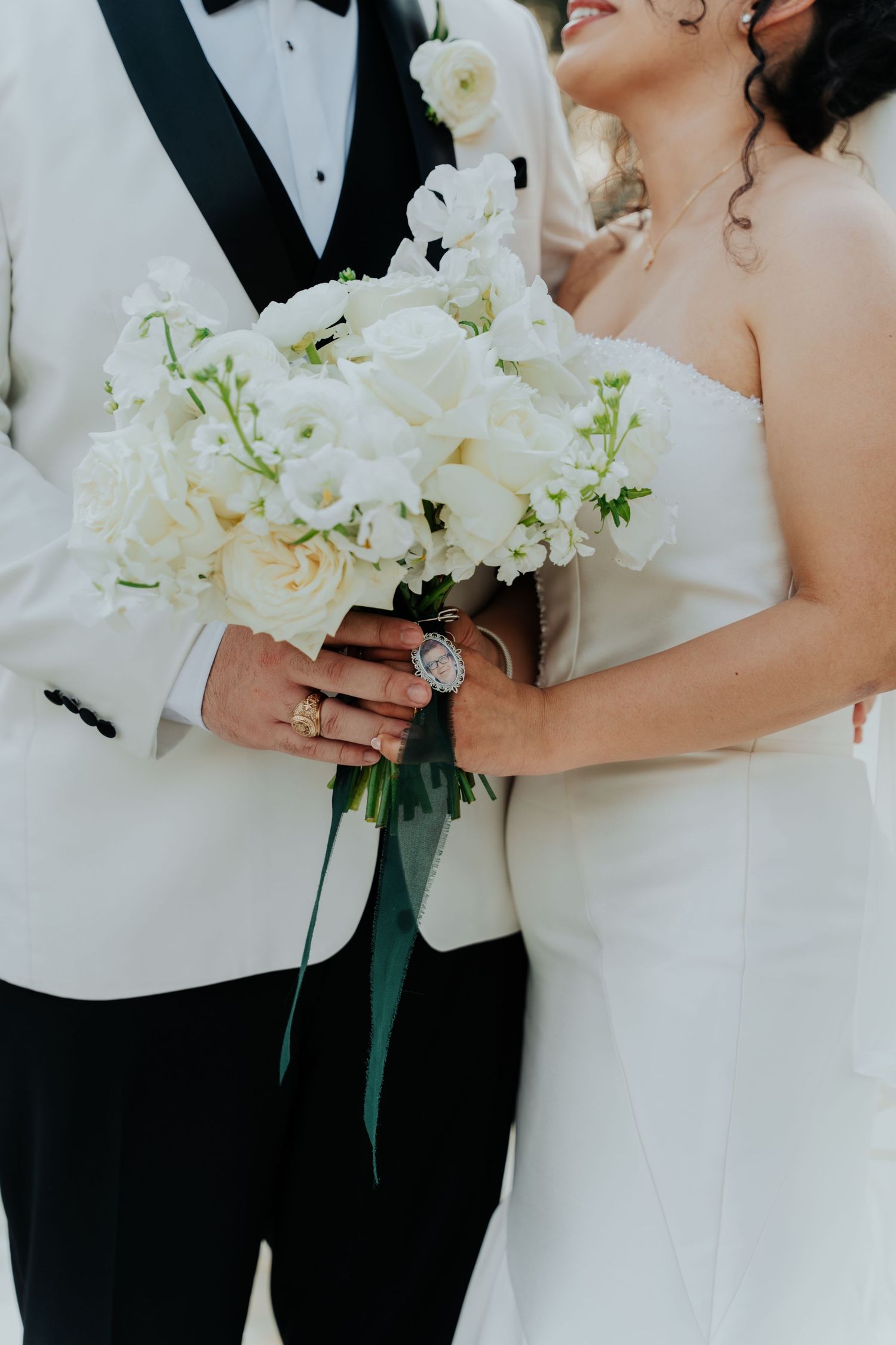 Newlyweds hold white floral bouquets while sharing romantic moment in formal attire.