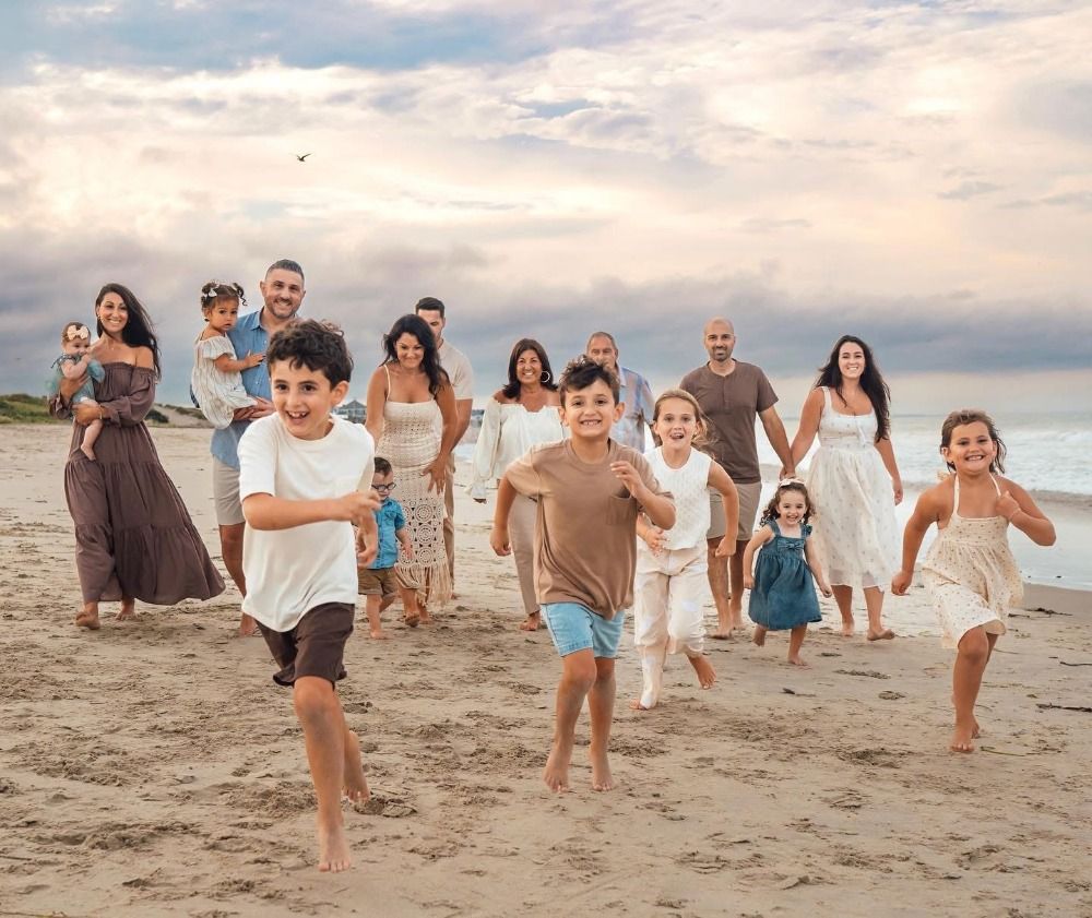A large extended family group having fun and running on the beach at sunset.