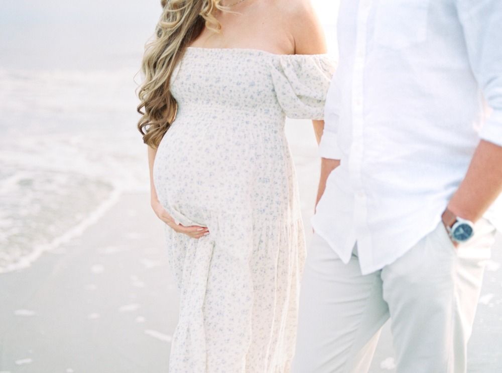 Ethereal beach maternity photos with soft white clothing and natural coastal lighting.