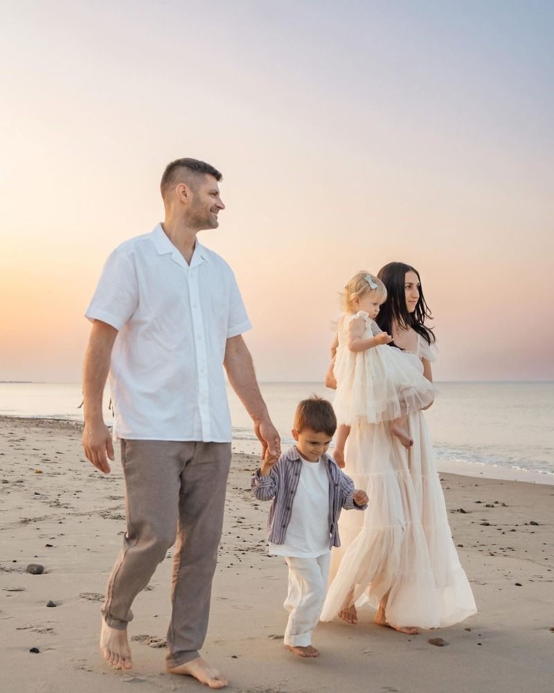 A family strolling barefoot along the beach during a peaceful sunset.