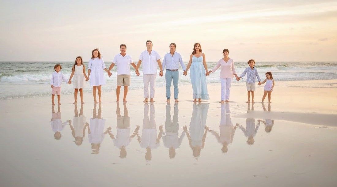 Family walking together along a scenic beach at sunset with reflections in the wet sand.