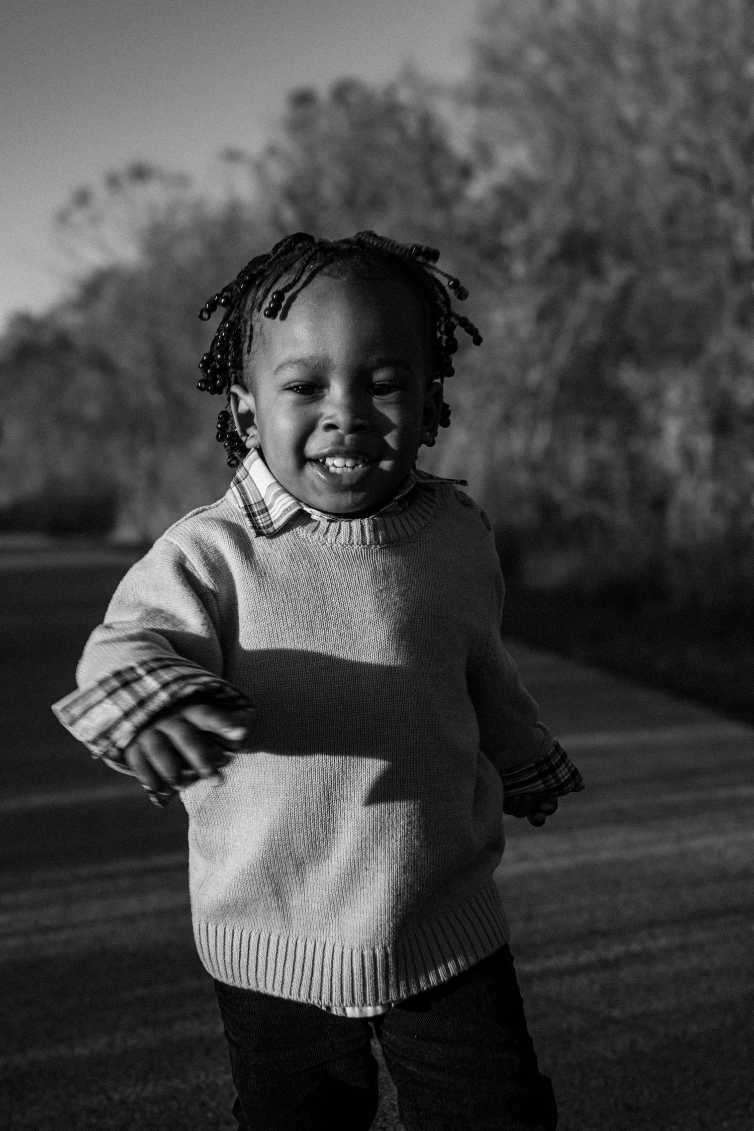 Black and white portrait of child in striped sweater outdoors.