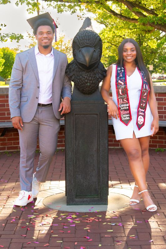 Graduation photoshoot with decorative pillar and rose petals on brick ground.