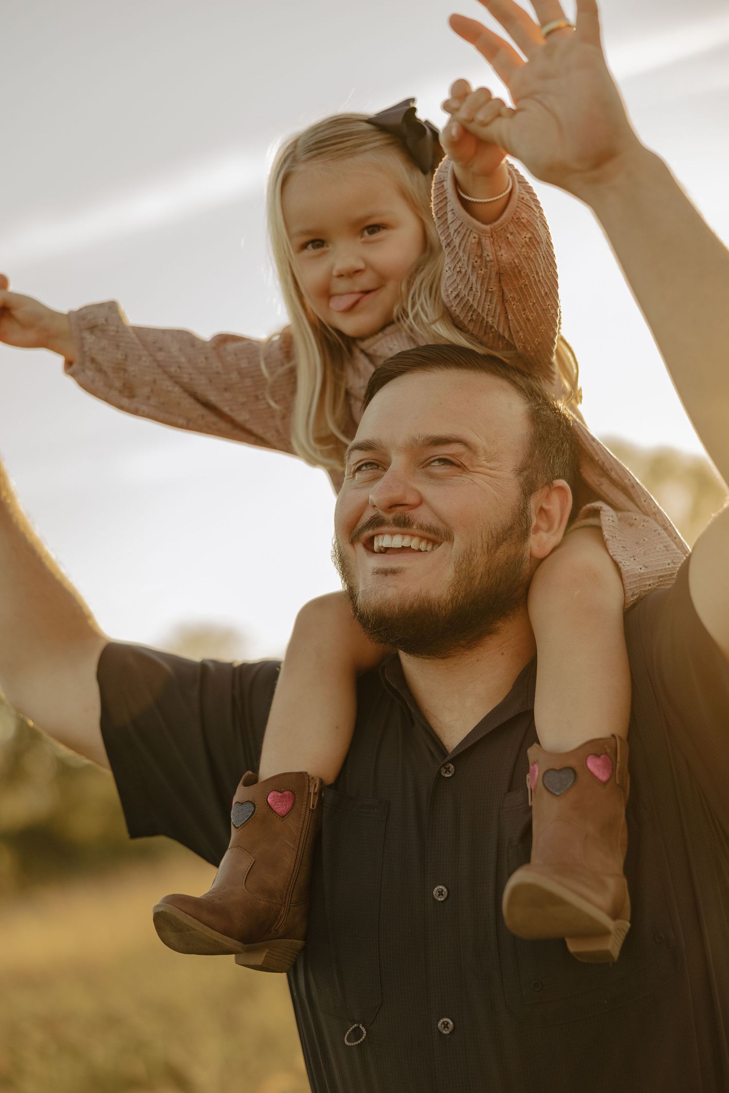 Family shares a playful moment in a sunlit field during golden hour.