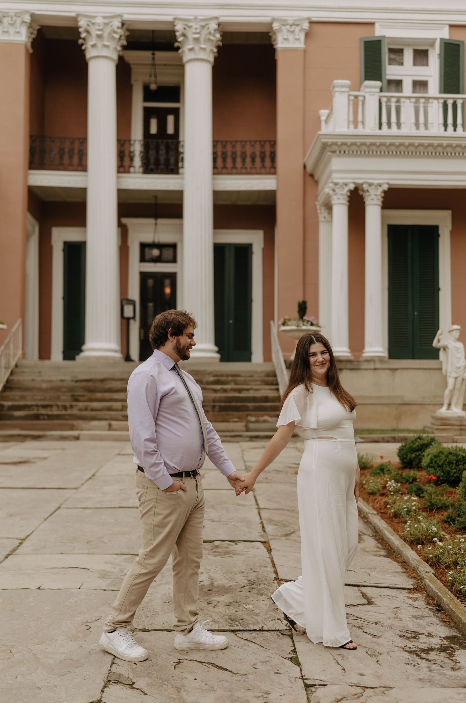 A couple shares a romantic moment while dancing outside a grand historic building.