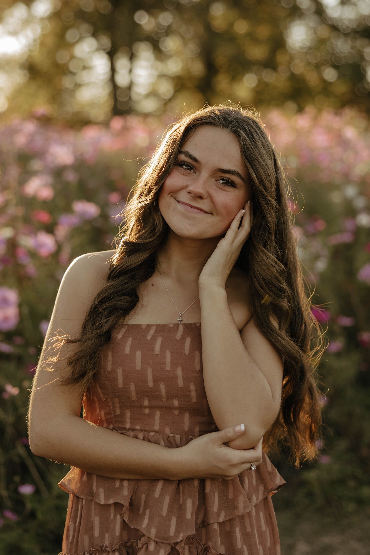 A portrait in a field of pink cosmos flowers during golden hour.