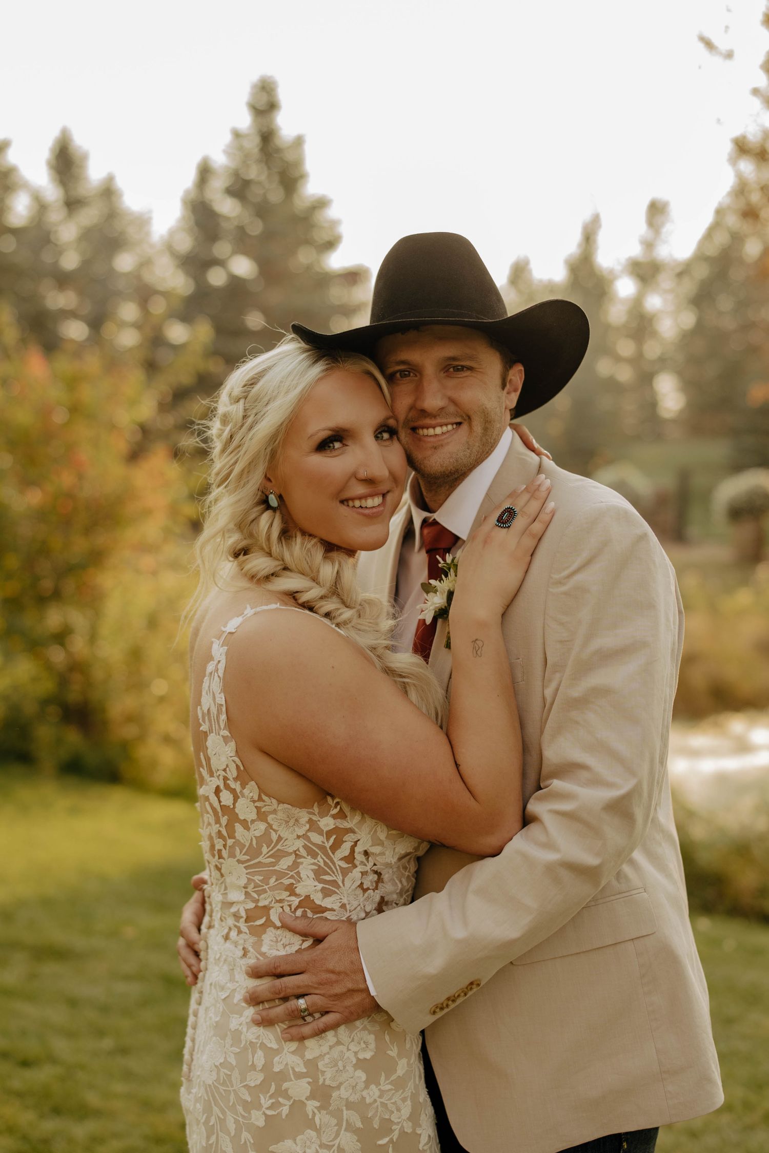 Intimate wedding portraits in a golden field at sunset with rustic western styling.