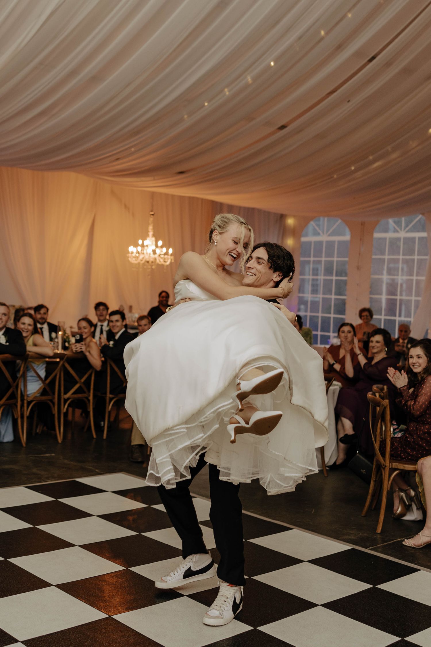 Dramatic dance moves on a black and white checkered floor during wedding reception.