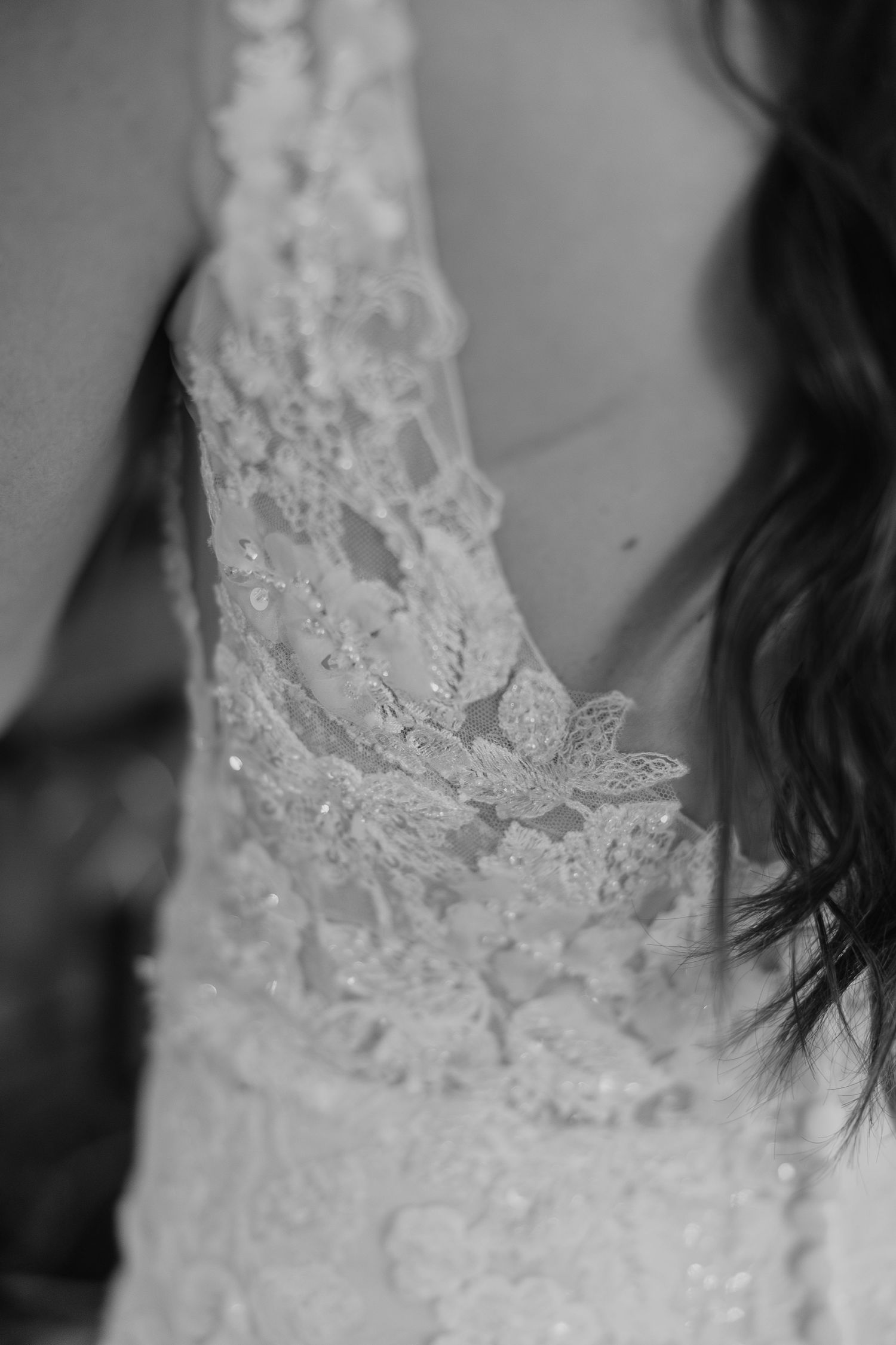 Close-up detail of delicate lace patterns on a white wedding dress.