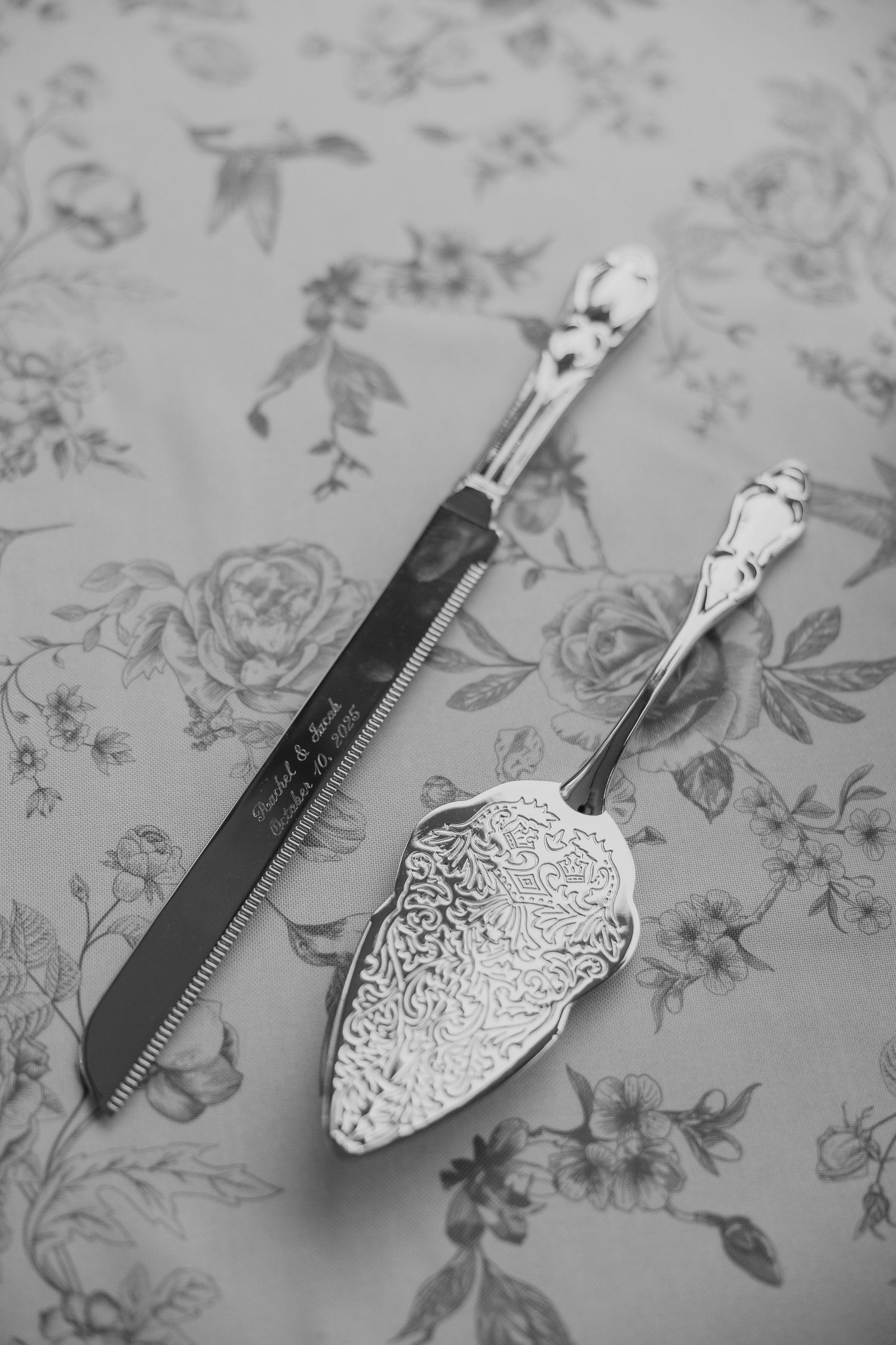 Vintage-style silver cake serving utensils displayed on floral patterned surface.