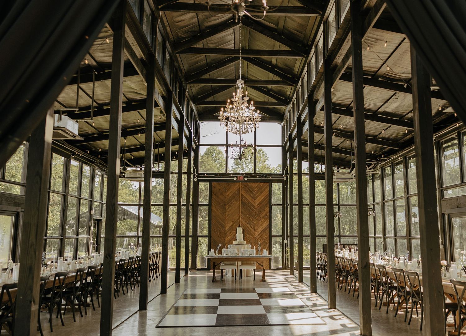 Interior panorama of a historic wooden hall with exposed beams, large windows, and elegant chandeliers creating a grand space.