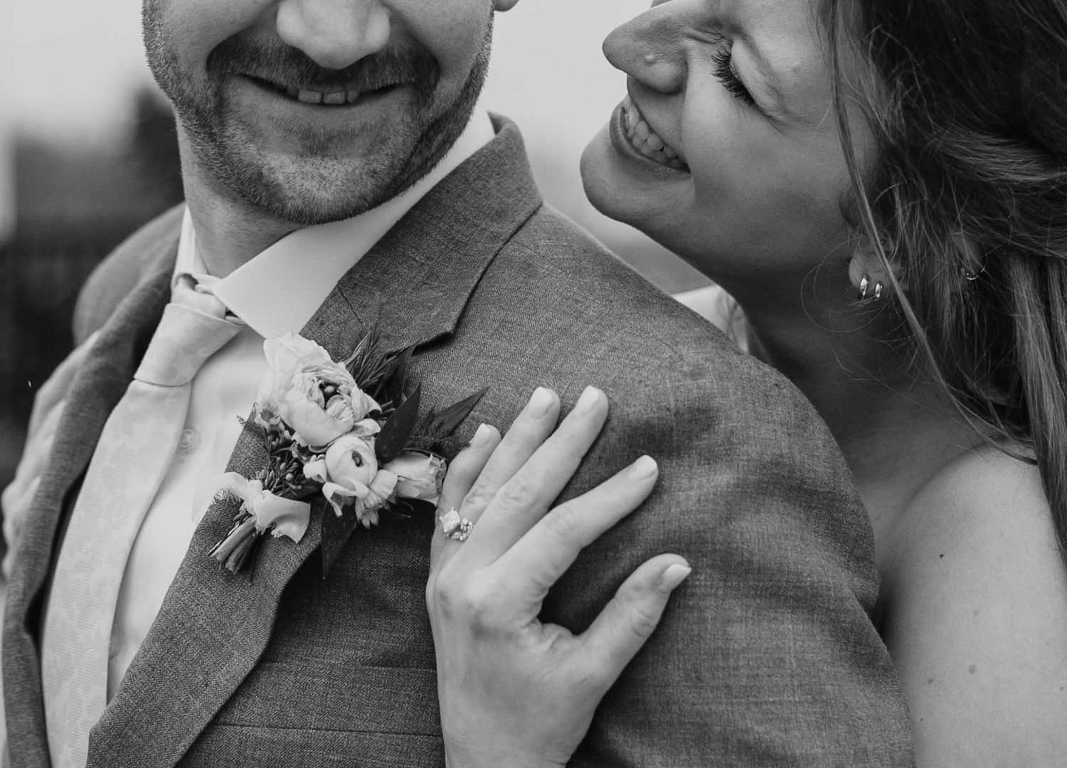 Close-up wedding portrait showing details of gray suit and floral boutonniere.