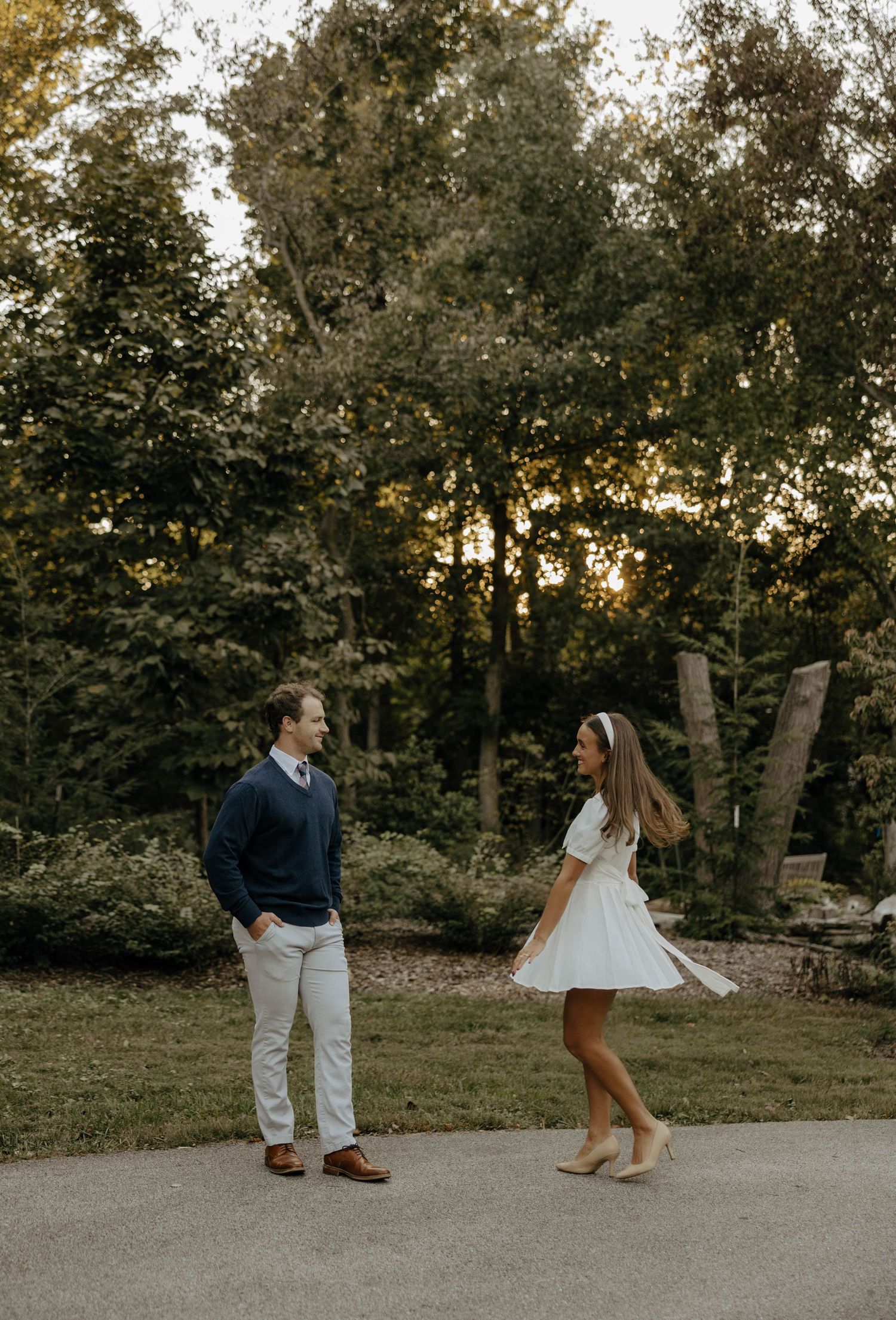 Playful sequence of a couple dancing and twirling on a path at sunset.