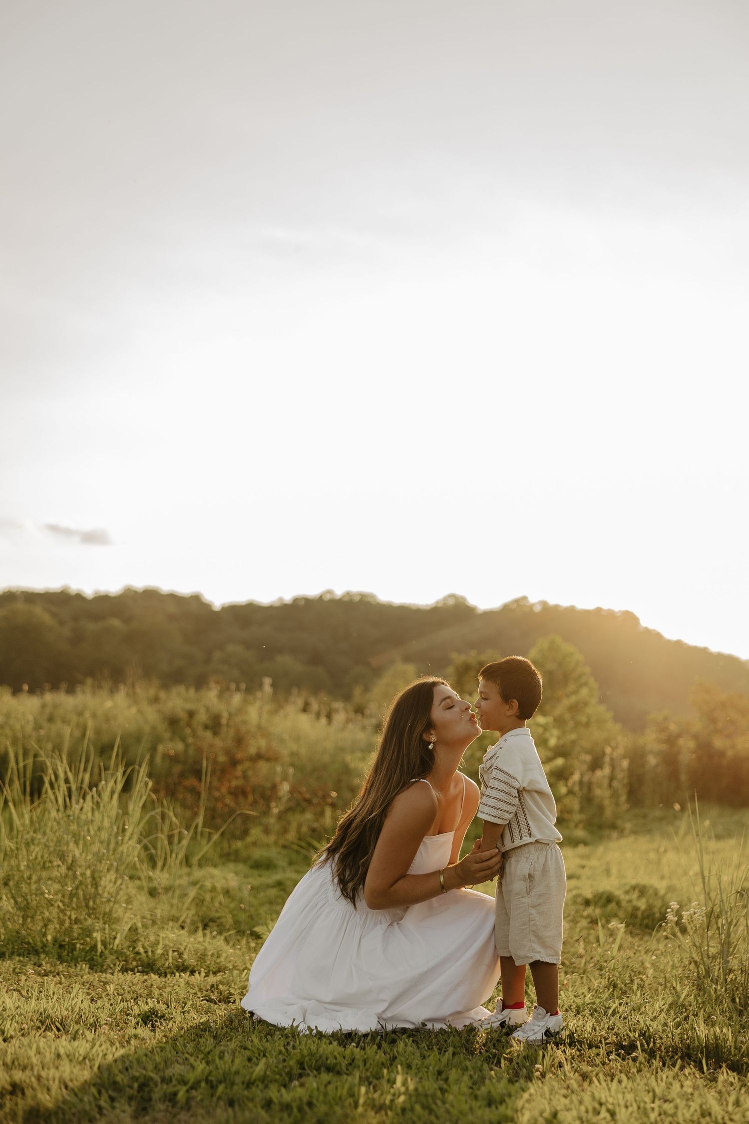 Golden hour photoshoot in a grassy field creates romantic ambiance.