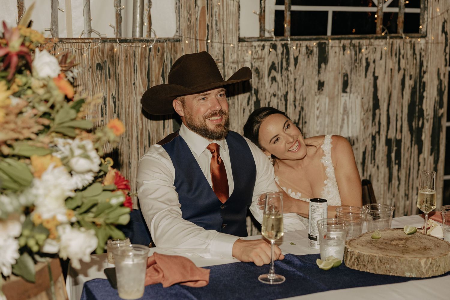 Candlelit reception table setting with rustic barn wood backdrop and floral arrangements.