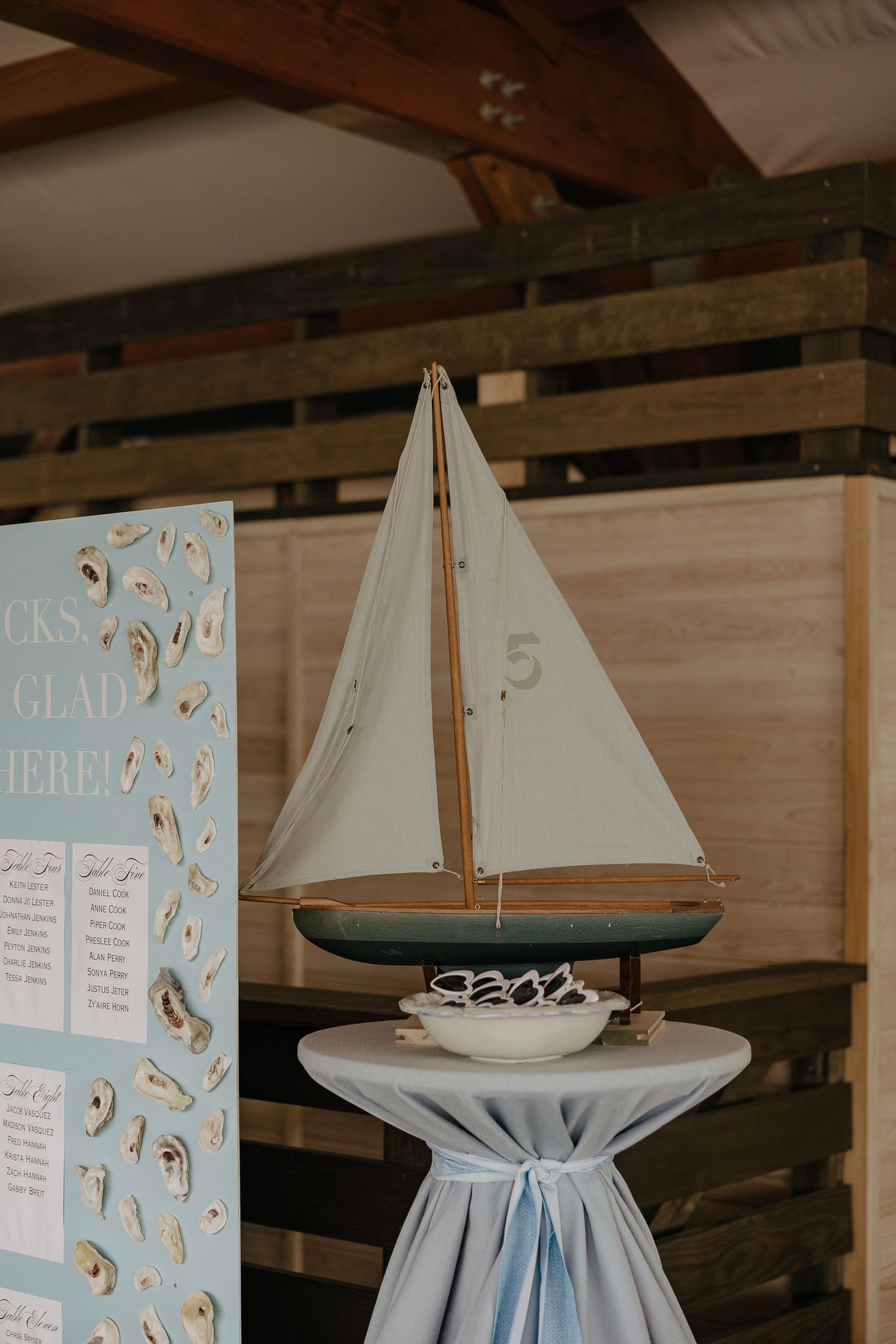 Nautical themed wedding decor featuring model sailboats and blue signage.