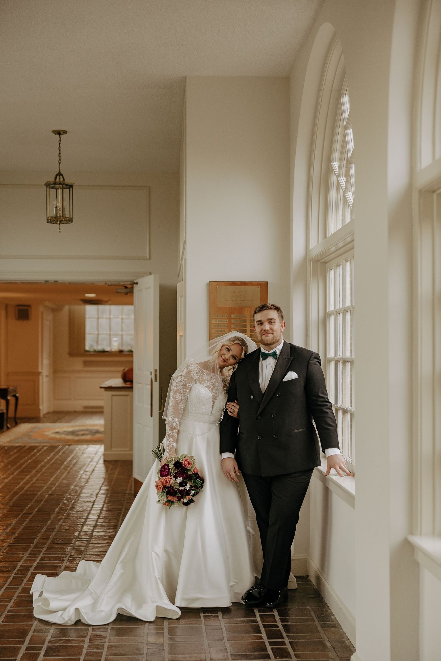 A series of four wedding photos showing a couple in formal attire walking and posing in a bright hallway with windows.