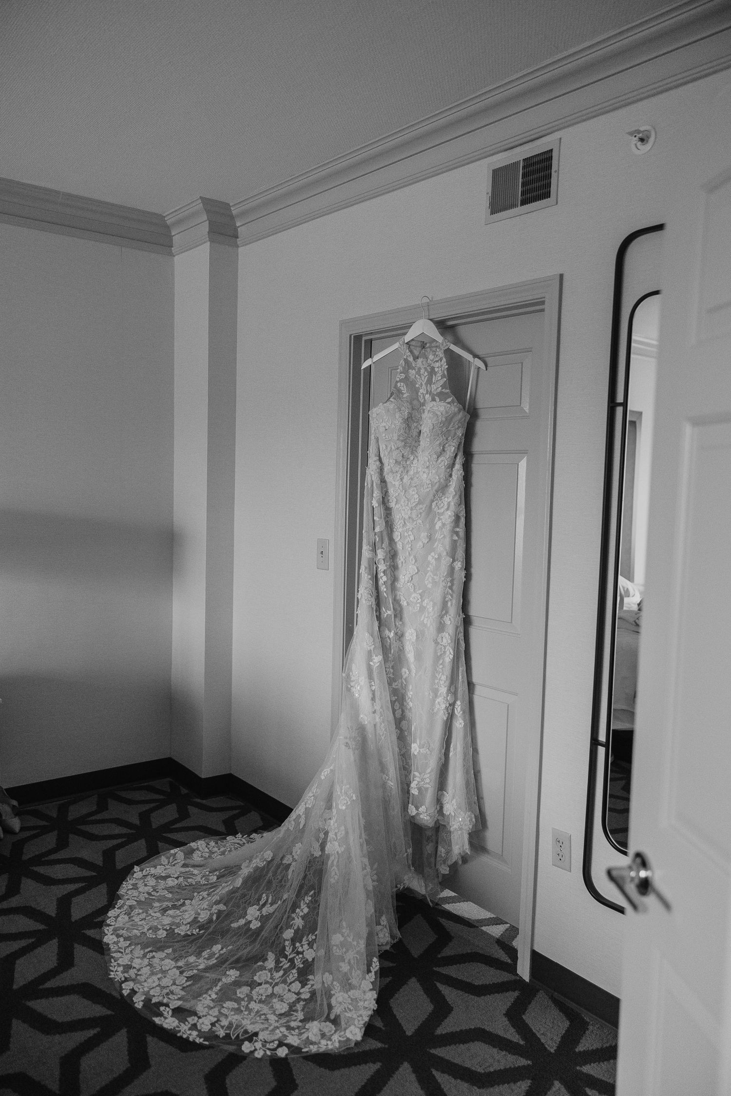 A black and white photo series showing a wedding dress hanging in different angles against white walls with geometric carpet.