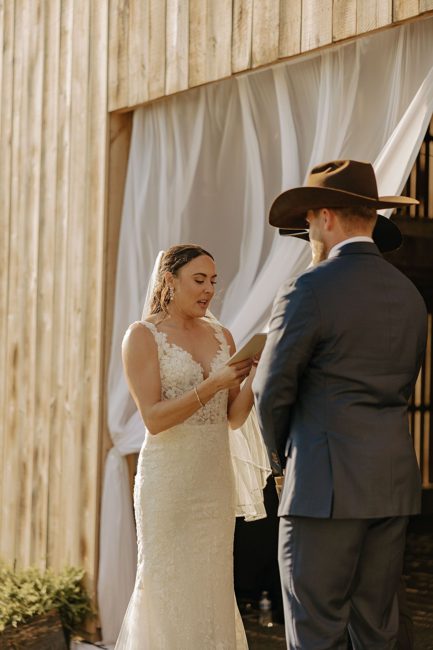 A couple stands together during an intimate barn wedding ceremony.