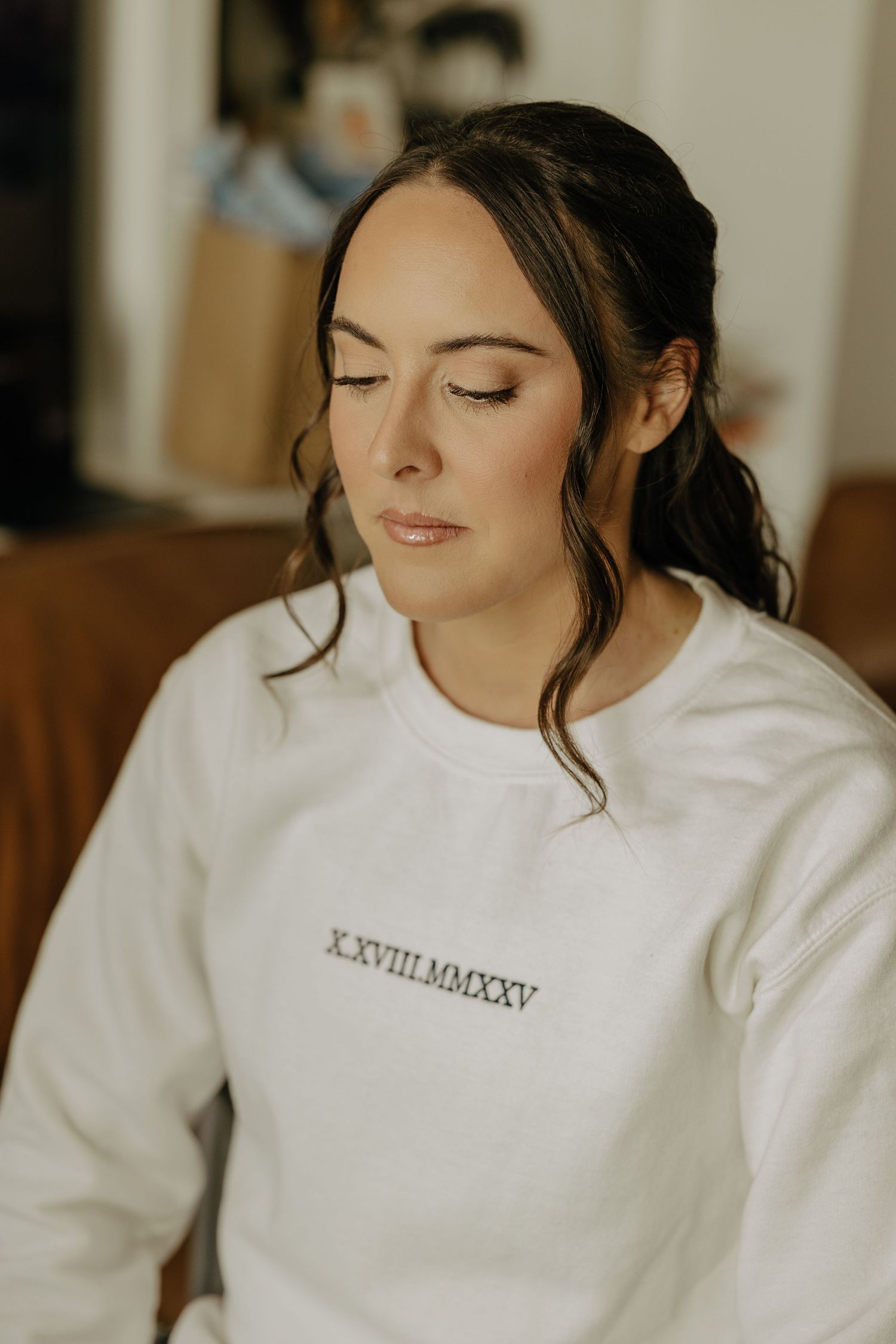 Close-up shots of someone wearing a white embroidered sweatshirt in soft lighting.