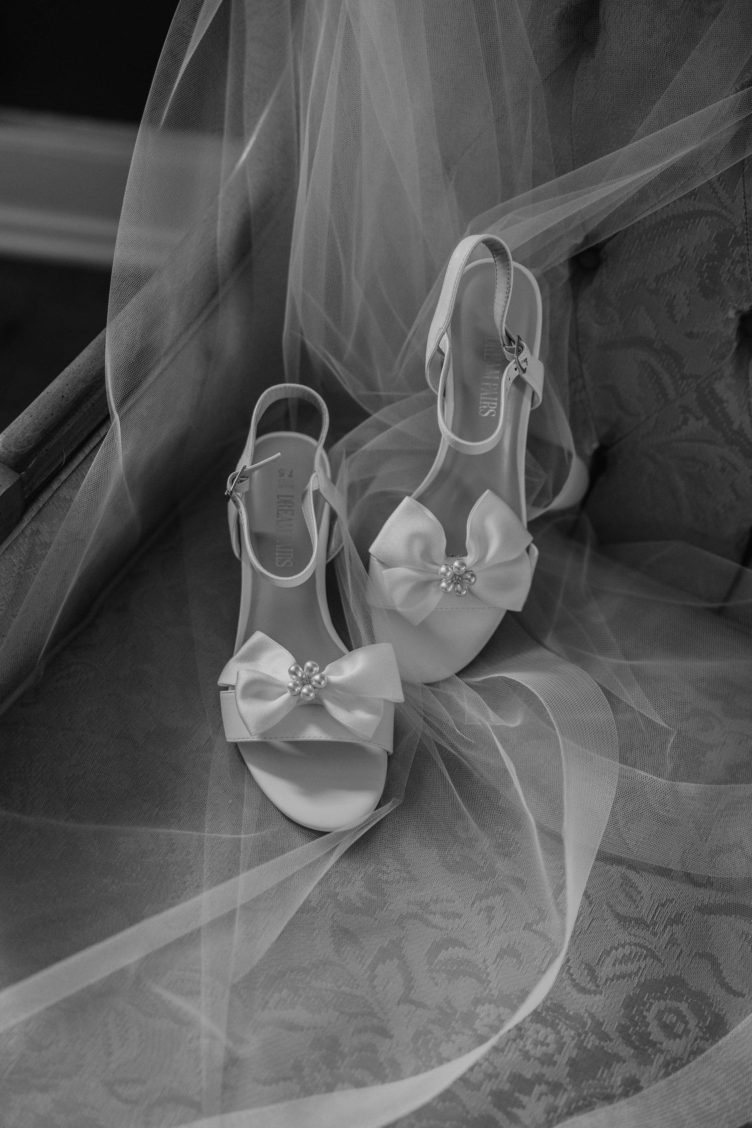 White bridal shoes and delicate tulle veil arranged artistically in black and white.