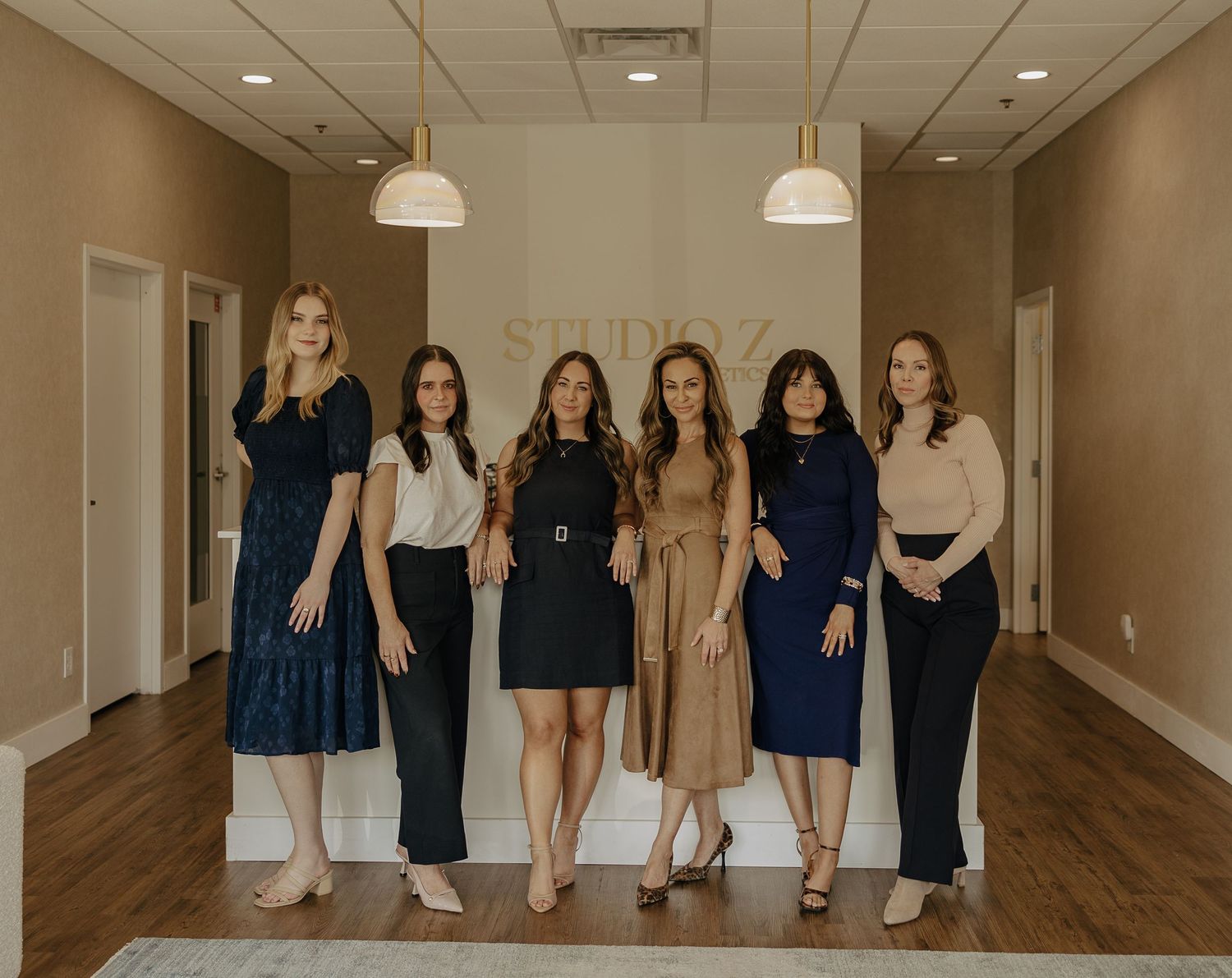 Professional group photo showing coordinated navy and neutral outfits in a modern studio space.