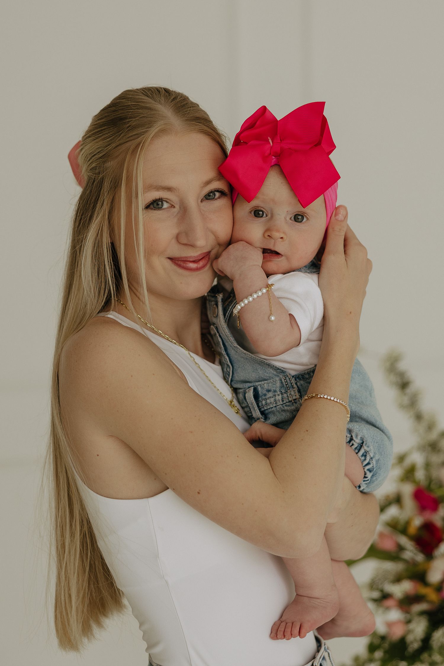 Tender moments photographed against a neutral wall with vibrant floral decorations.