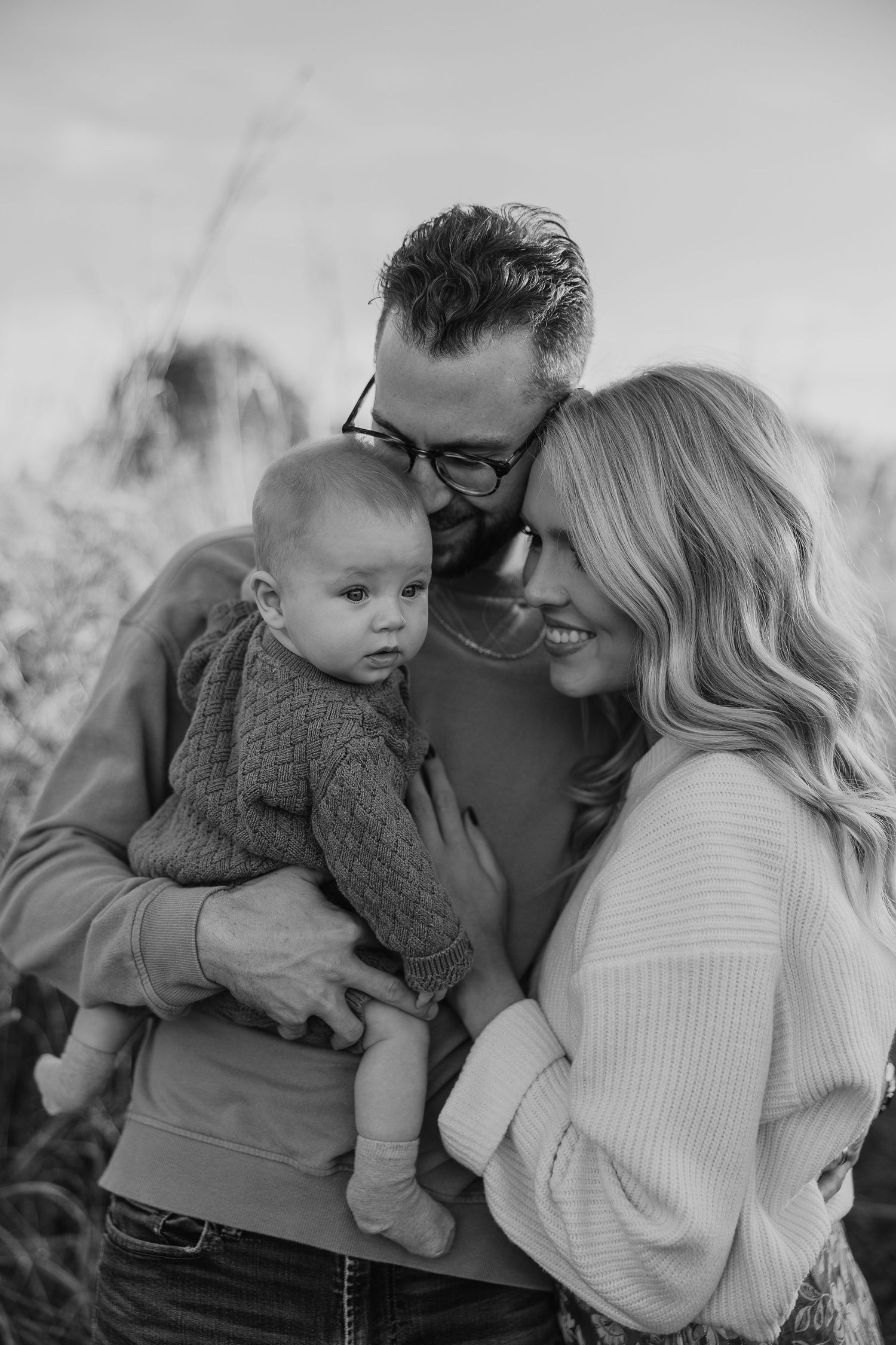 An intimate black and white family portrait showing tender moments outdoors.
