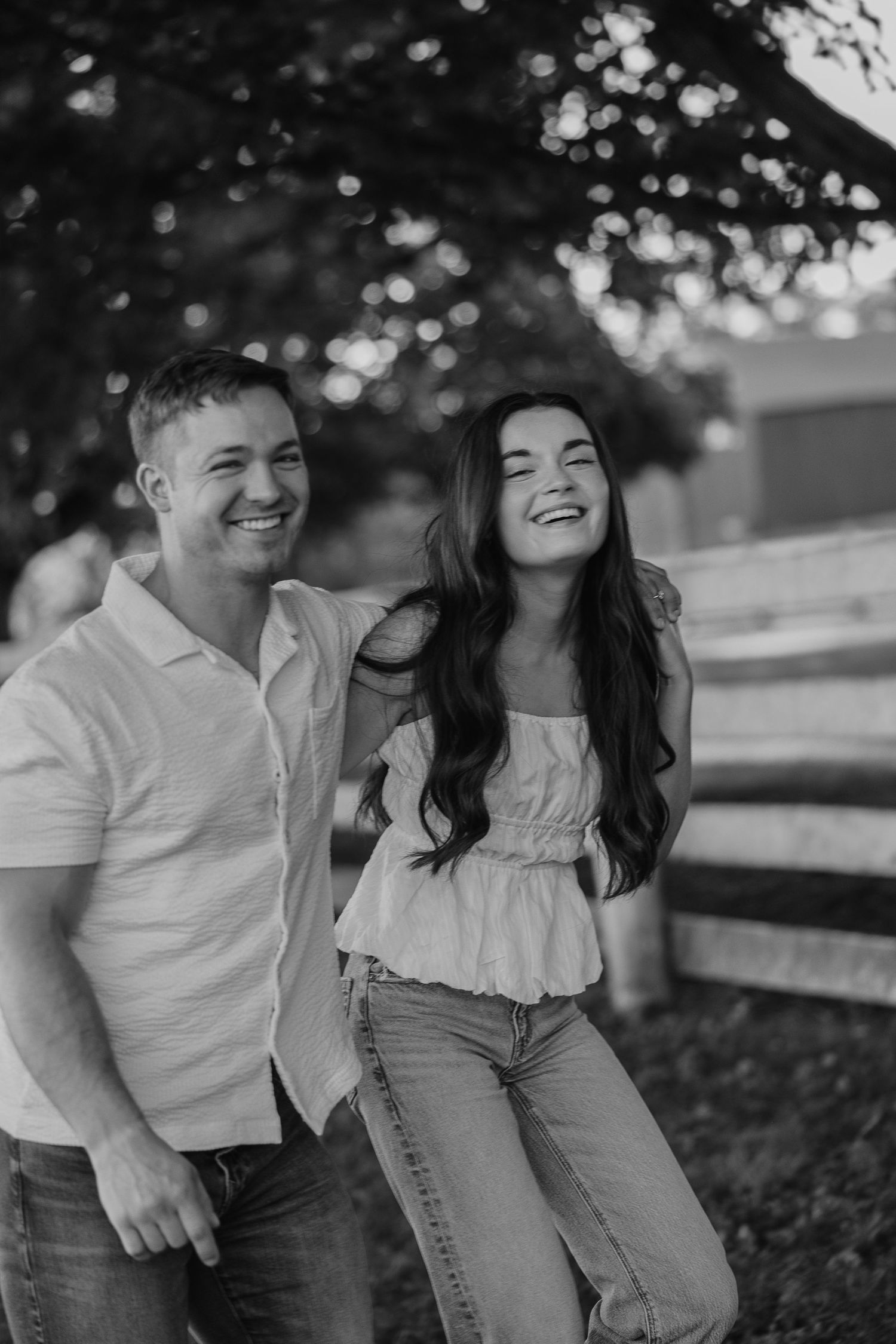 Couple sharing joyful moments outdoors with natural lighting and trees in background.