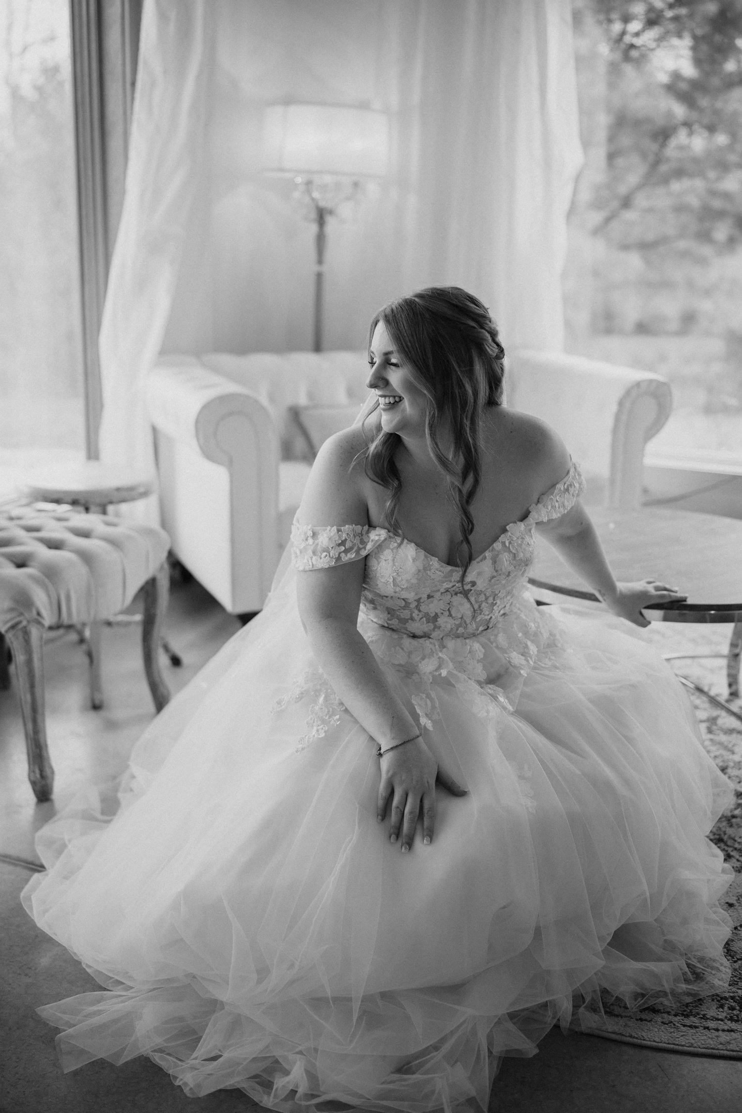Elegant bridal portrait on white chaise lounge with soft window light.