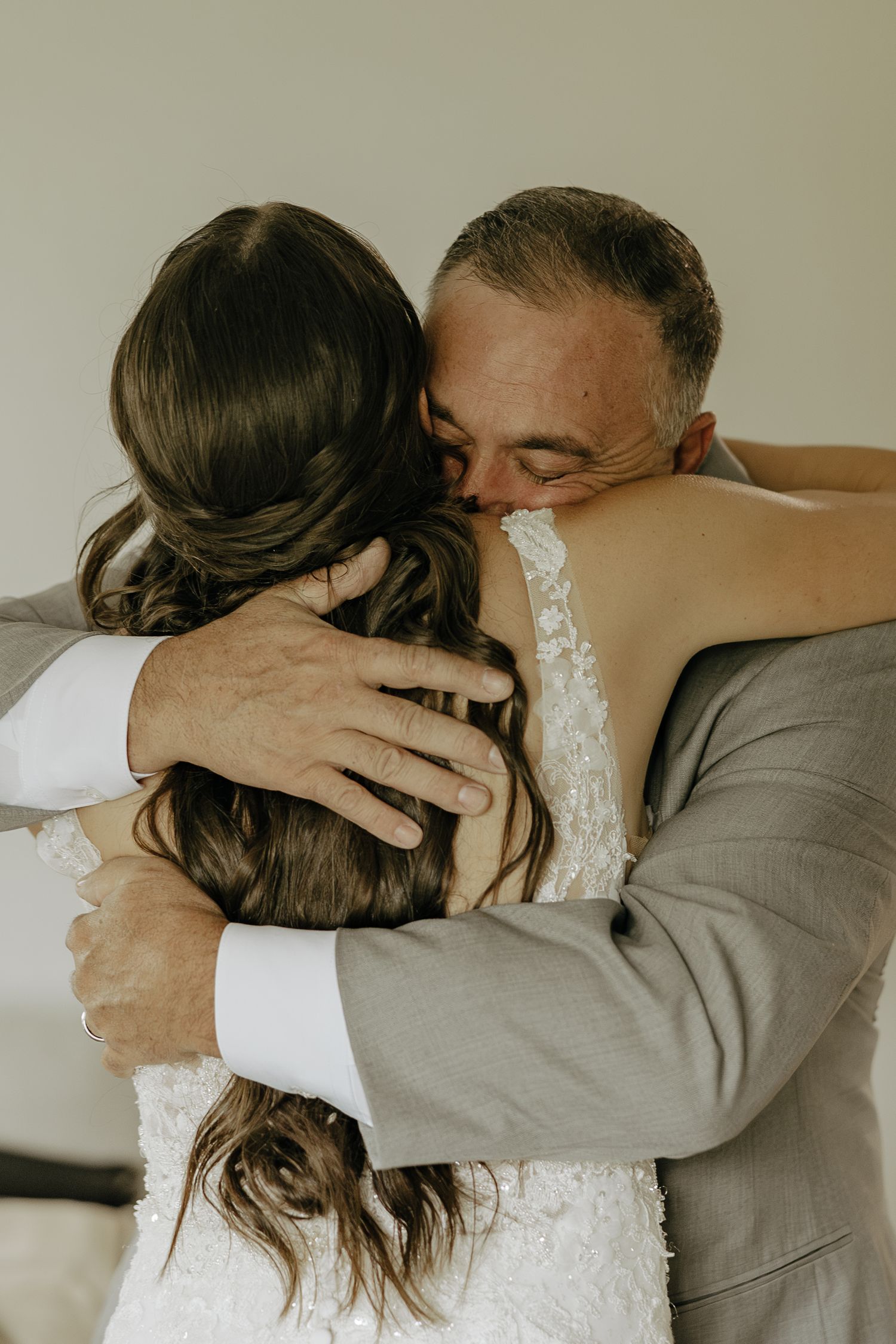 Emotional embrace between two people, one wearing a white lace dress.
