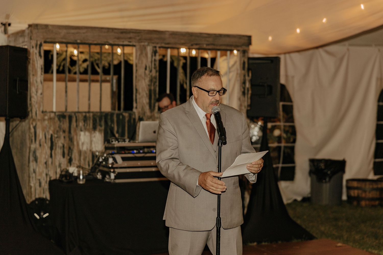 Wedding reception setup in a tent with string lights and elegant decor creating a warm ambiance.