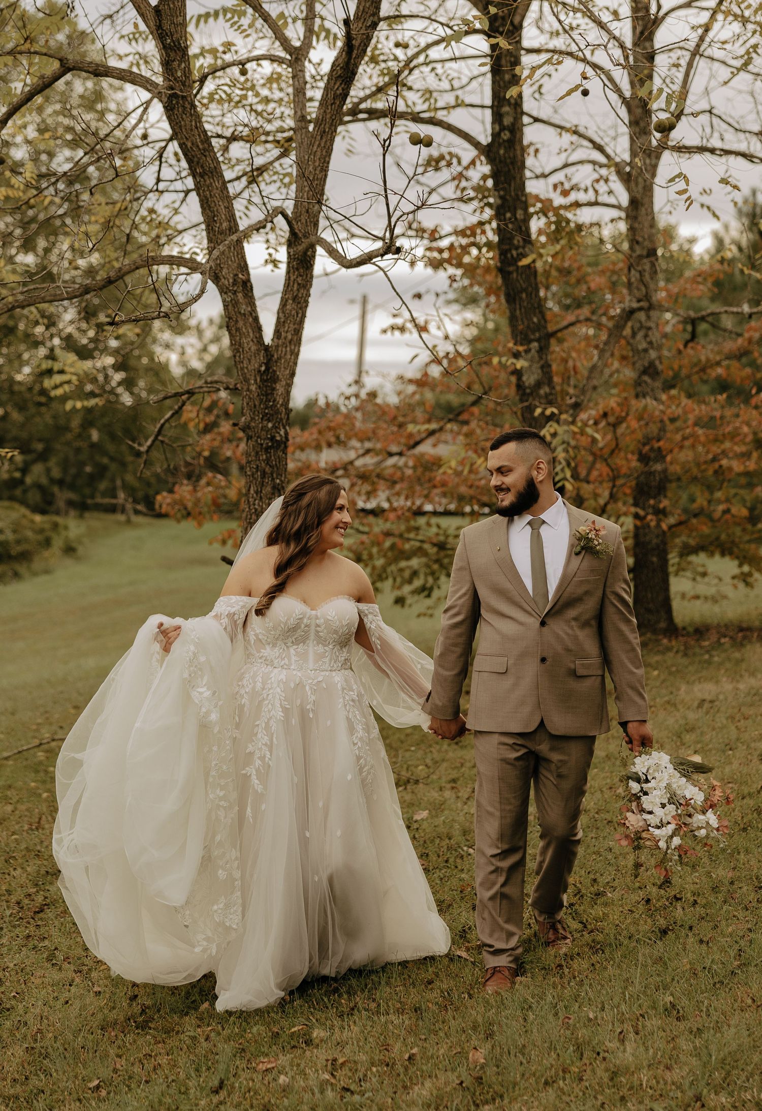 Romantic autumn wedding portrait in a field with flowing white dress and tan suit.