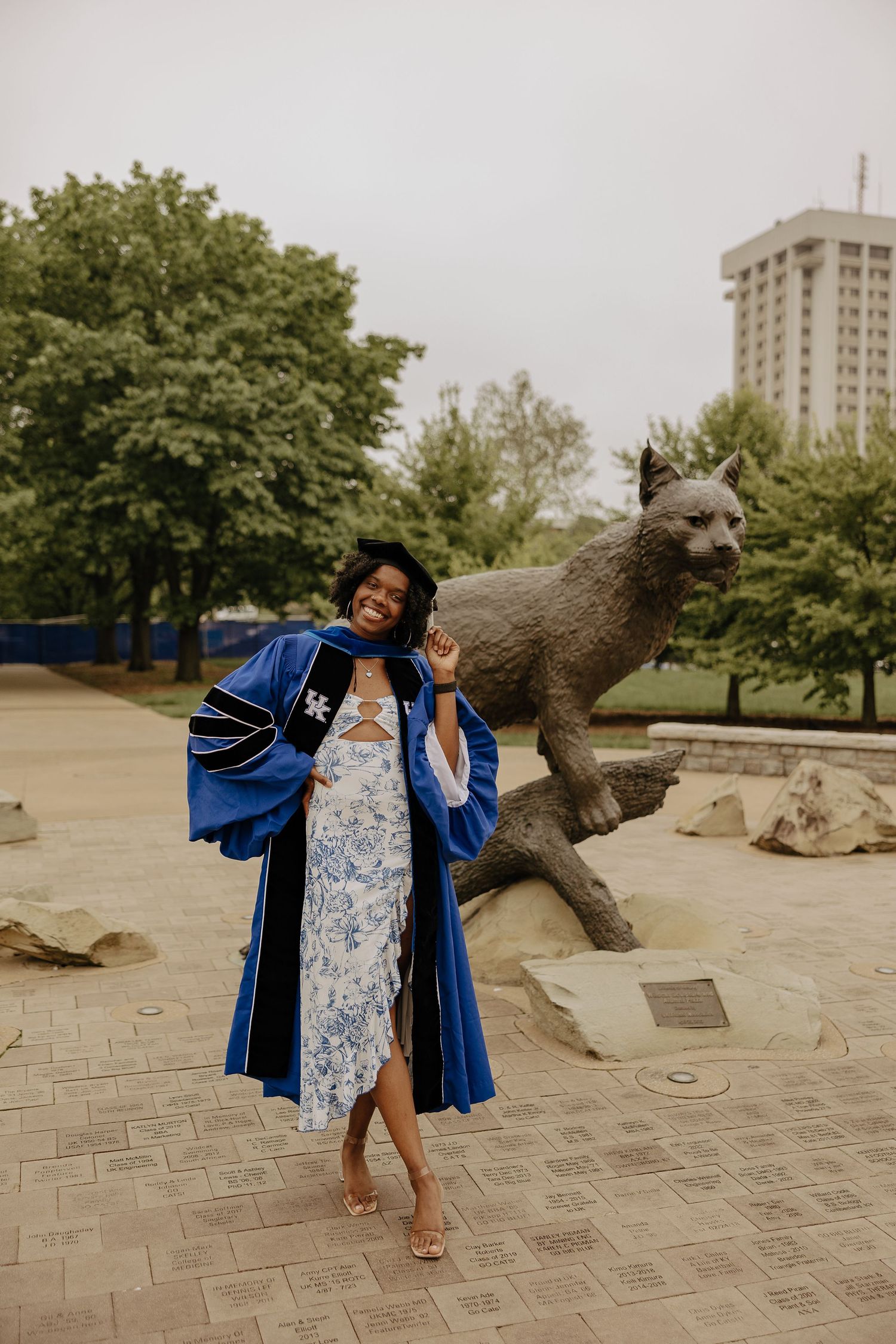 Graduation celebration photos with university mascot statue and blue doctoral robes.