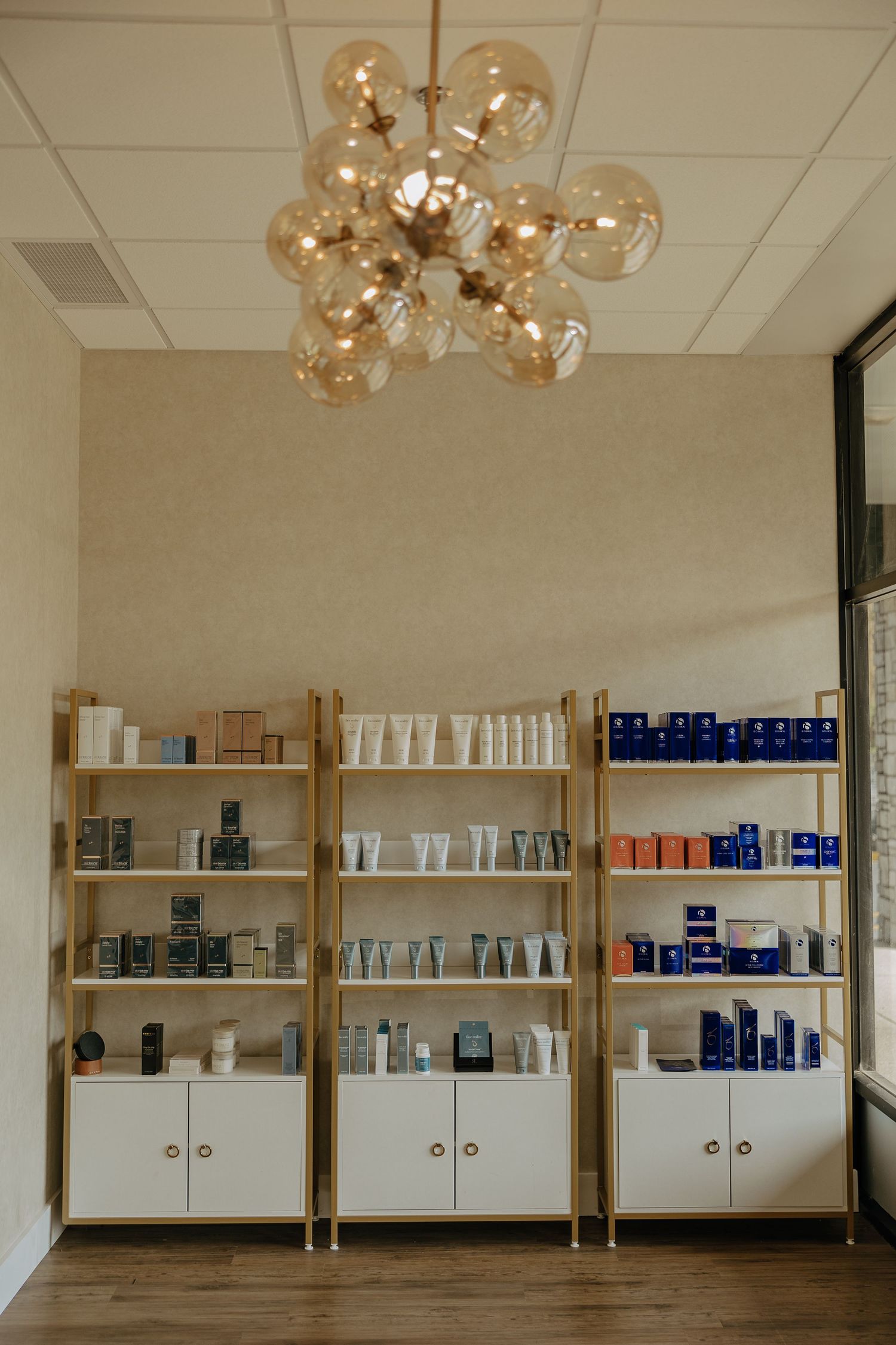 Aesthetic spa interior with globe chandelier and wooden product shelving units.