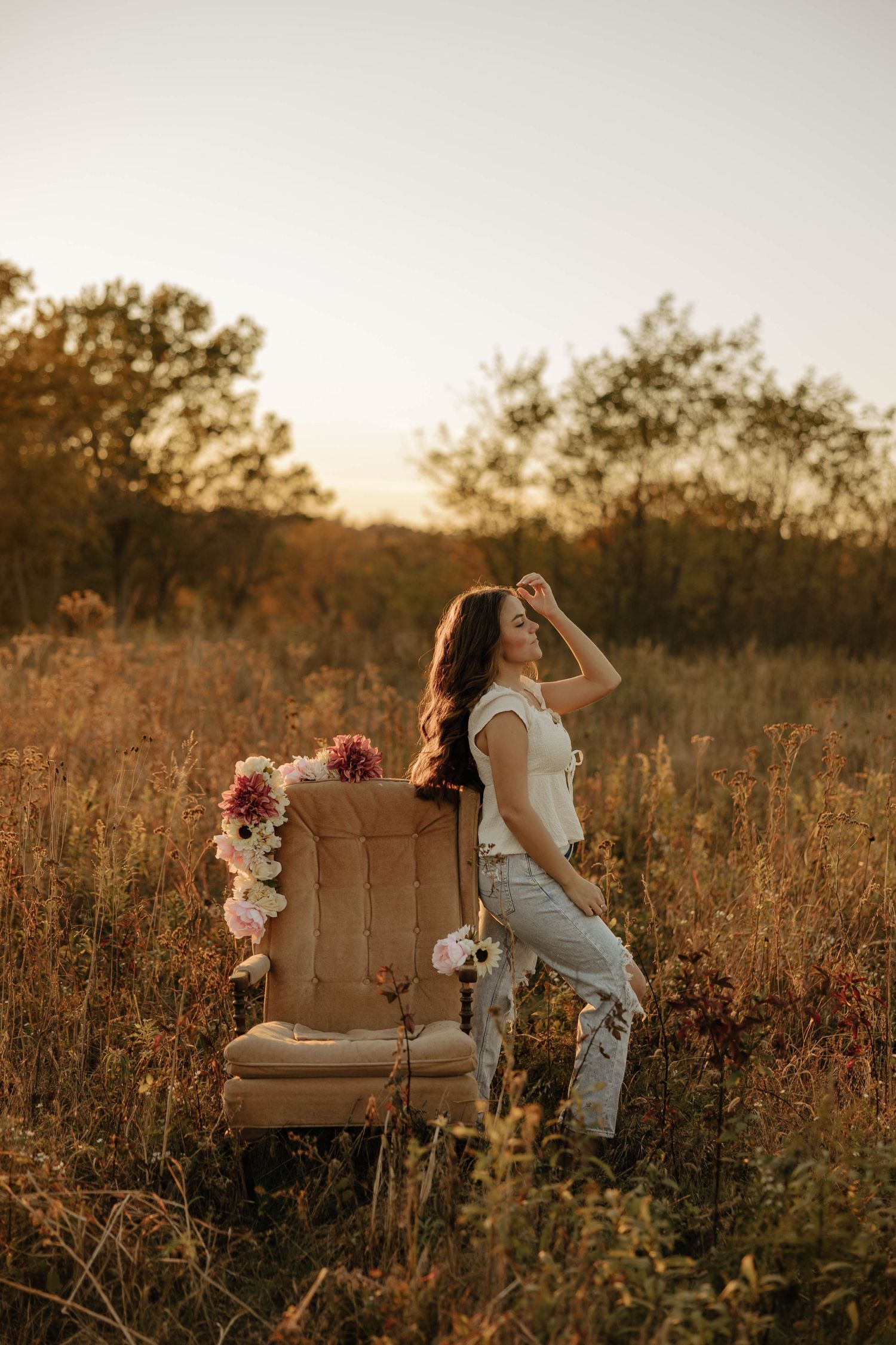 A vintage armchair decorated with flowers sits in a golden sunset field.