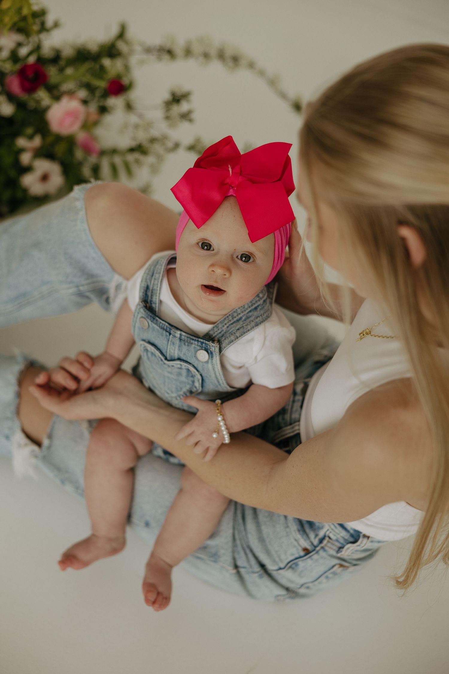 Sweet candid moments captured on a light backdrop with pink and red flowers.