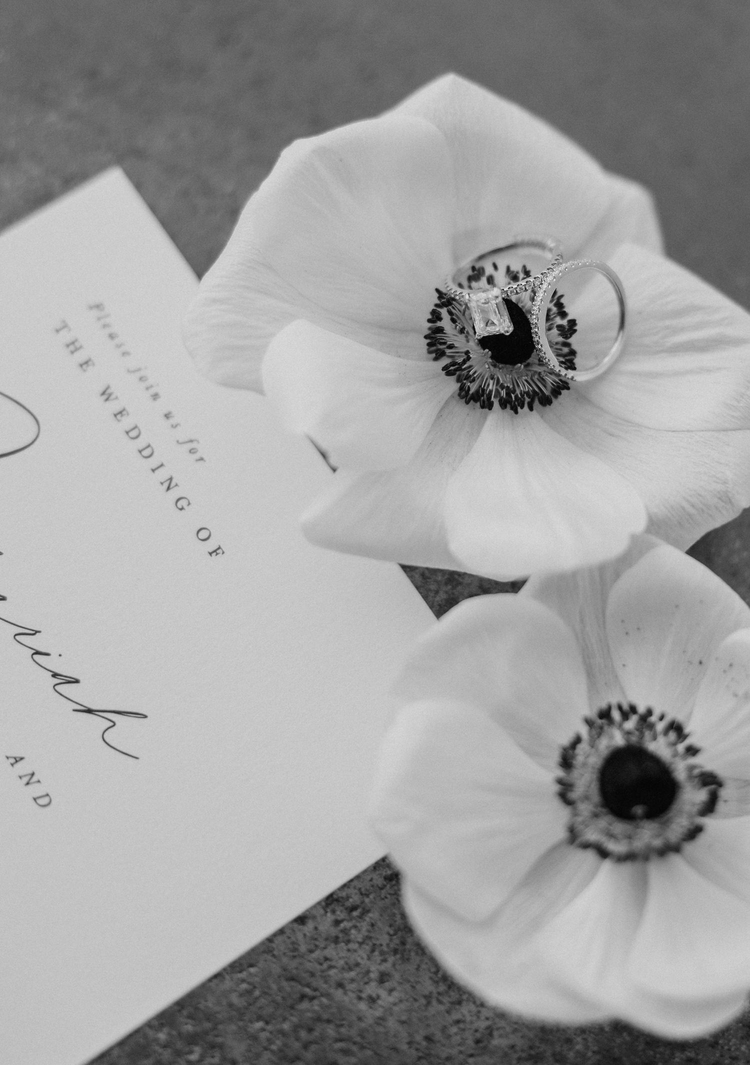 Delicate white anemone flowers arranged with handwritten wedding stationery in black and white.