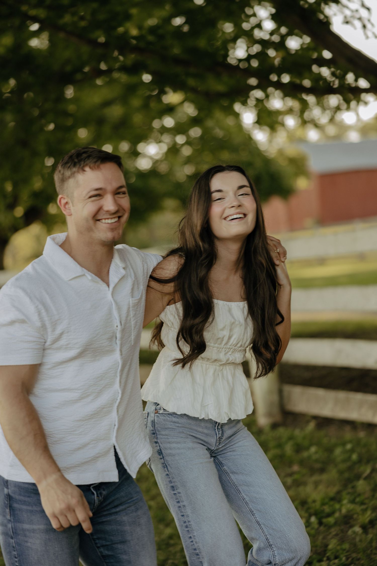 Couple laughing together in a casual outdoor photoshoot wearing white and denim.