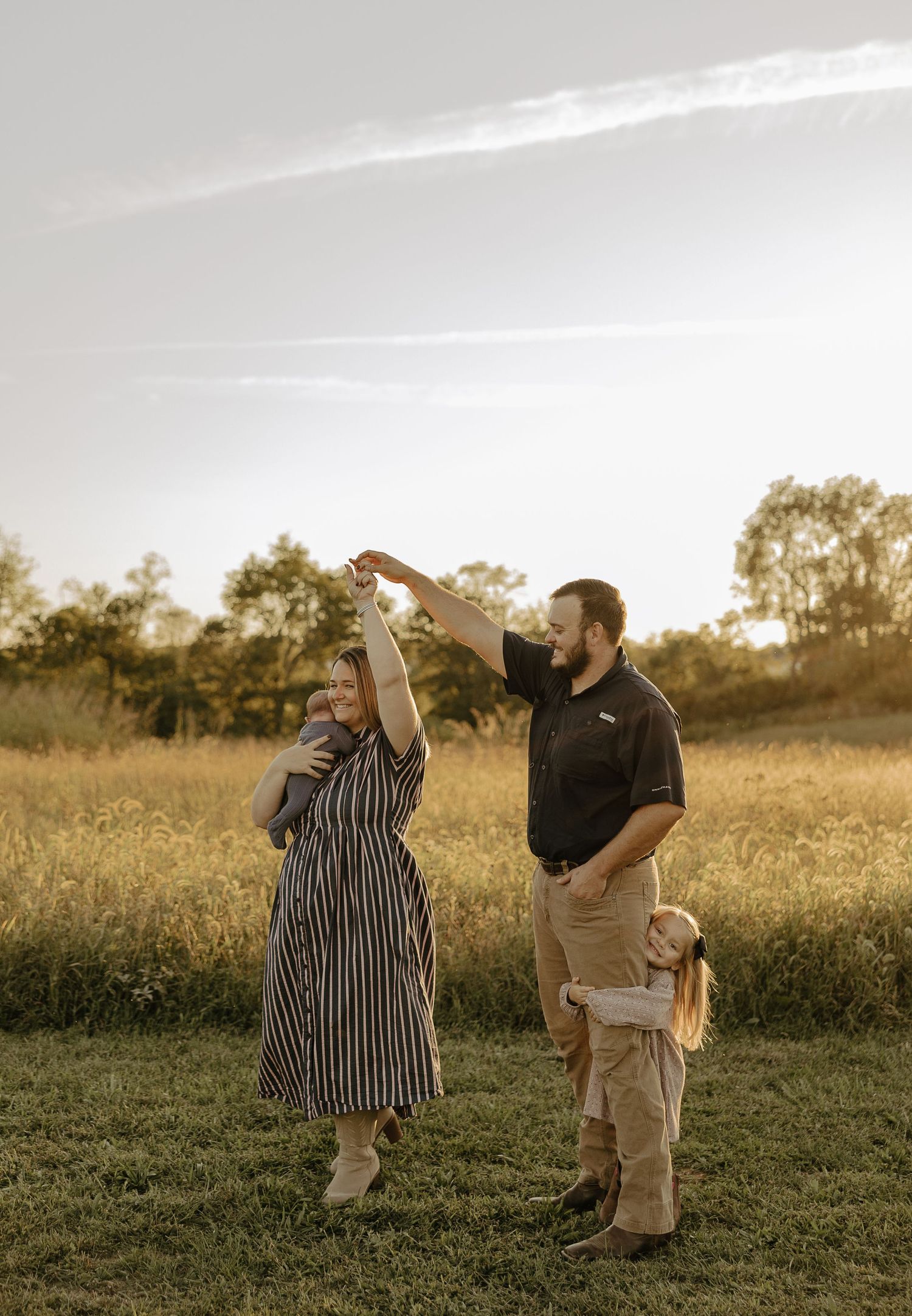 People playfully interact in a sun-drenched field during golden hour.