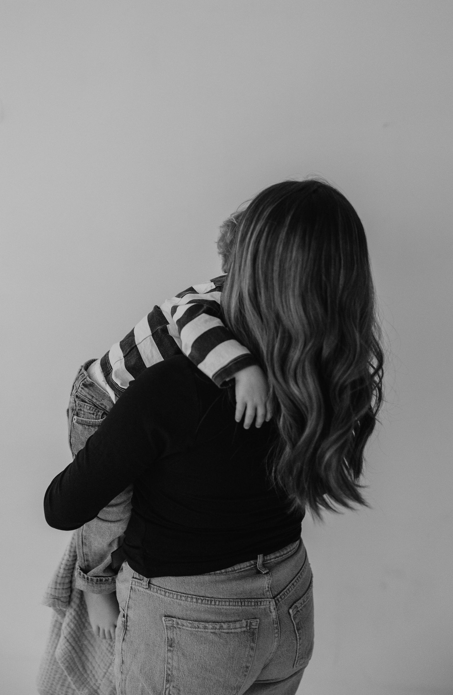 A person in denim jeans and black top shown from behind in a series of artistic black and white photographs.