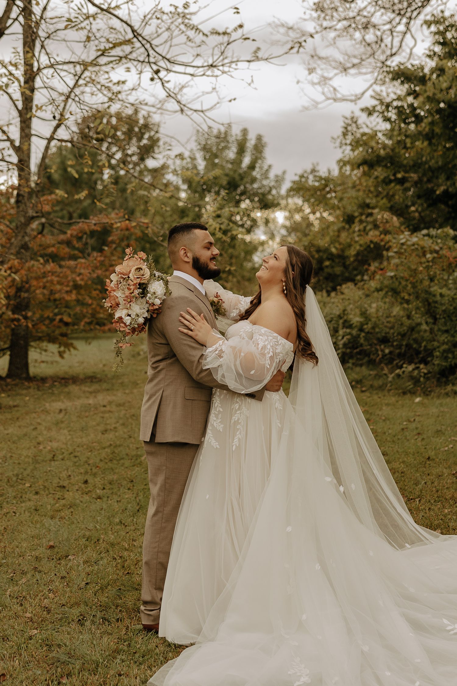 Couple sharing intimate moment during outdoor wedding photos in autumn setting.
